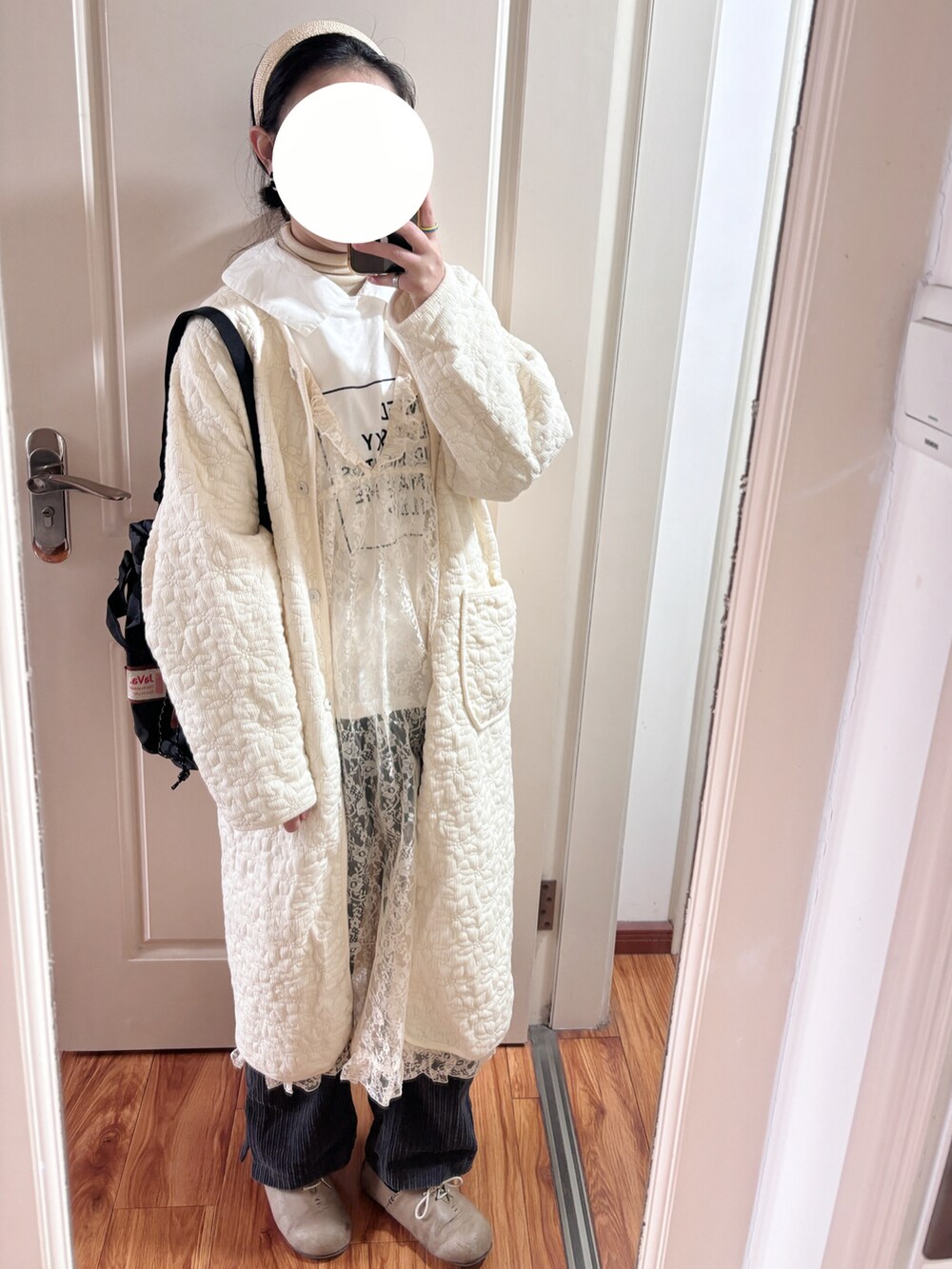 ホワイト系のワンピース、ホワイト系のノーカラーコート、ブラック系のショルダーバッグを着用したレディースの冬コーディネートの3枚目の写真