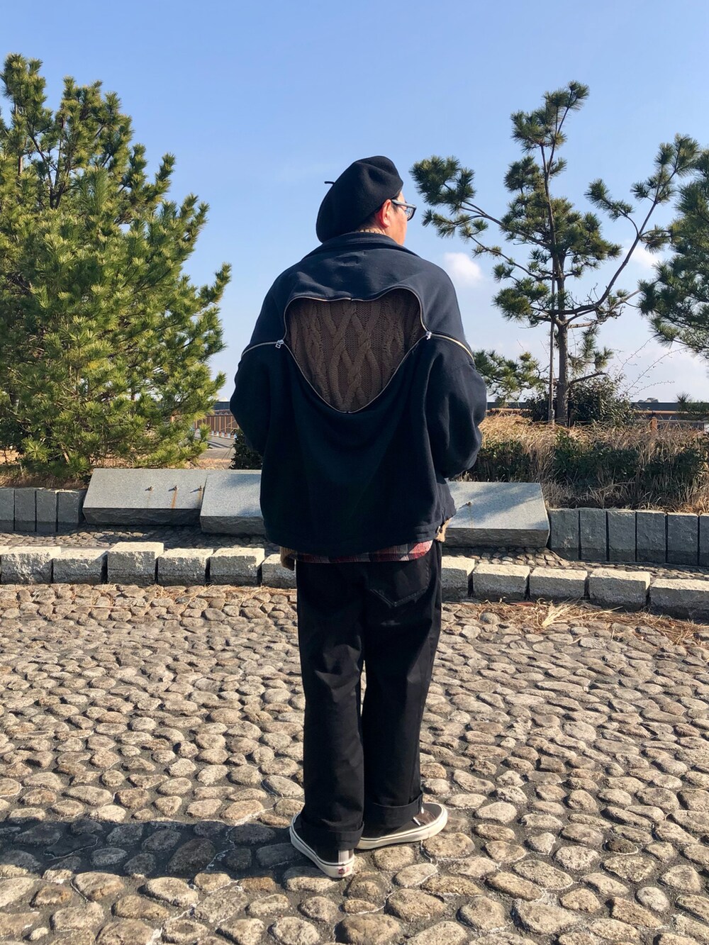 ブラック系のジャケット/アウター、ブラウン系のニット/セーター、ブラック系のチノパンツを着用したメンズの冬コーディネートの3枚目の写真