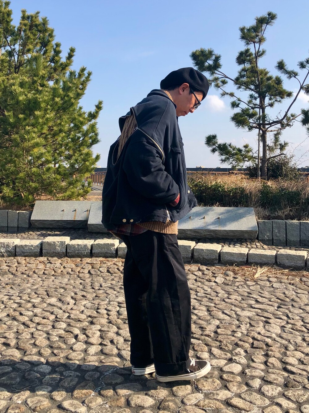 ブラック系のジャケット/アウター、ブラウン系のニット/セーター、ブラック系のチノパンツを着用したメンズの冬コーディネートの5枚目の写真