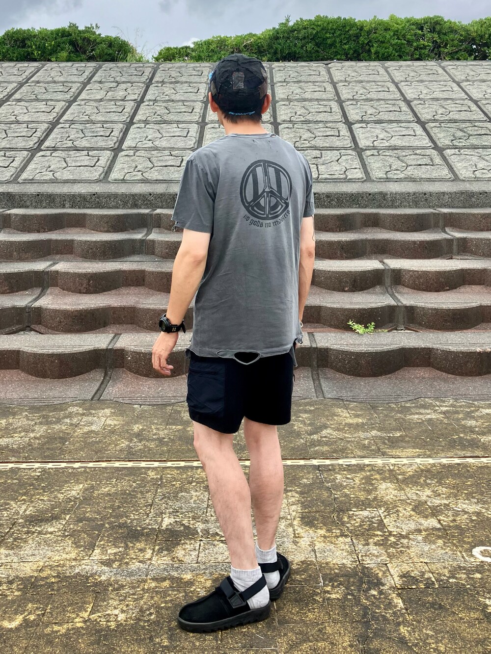 グレー系のTシャツ/カットソー、ブラック系のパンツ、ブラック系のスリッポンを着用したメンズの夏コーディネートの2枚目の写真