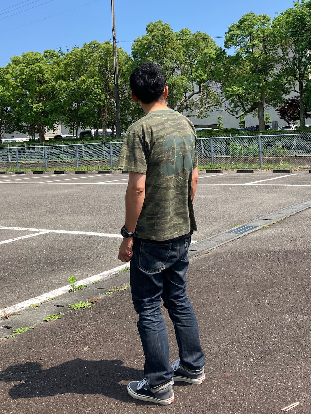 グリーン系のTシャツ/カットソー、ブルー系のデニムパンツ、ブルー系のスニーカーを着用したメンズの夏コーディネートの2枚目の写真