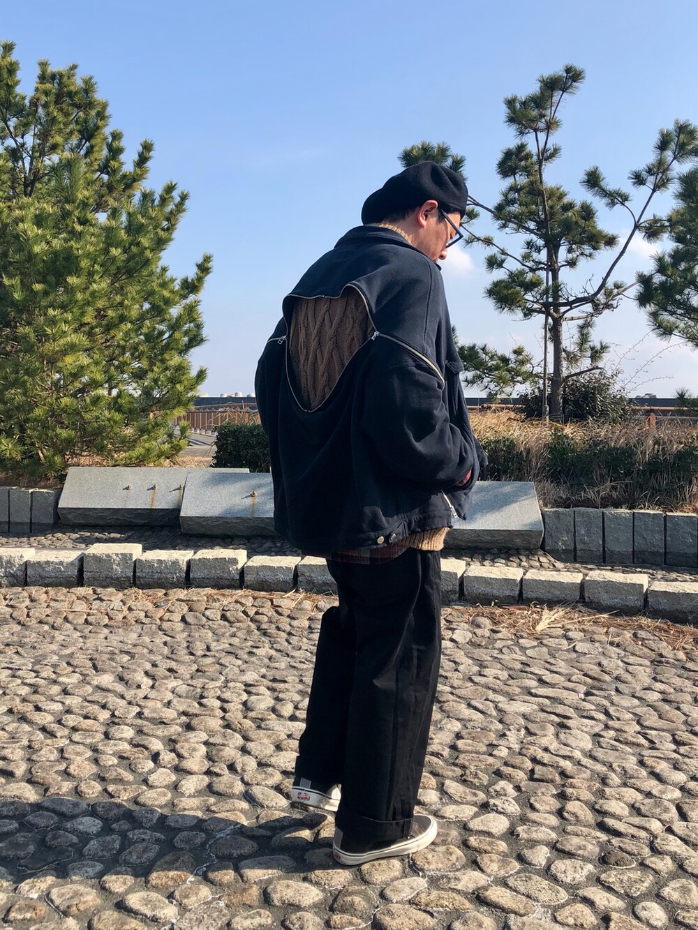 ブラック系のジャケット/アウター、ブラウン系のニット/セーター、ブラック系のチノパンツを着用したメンズの冬コーディネートの4枚目の写真