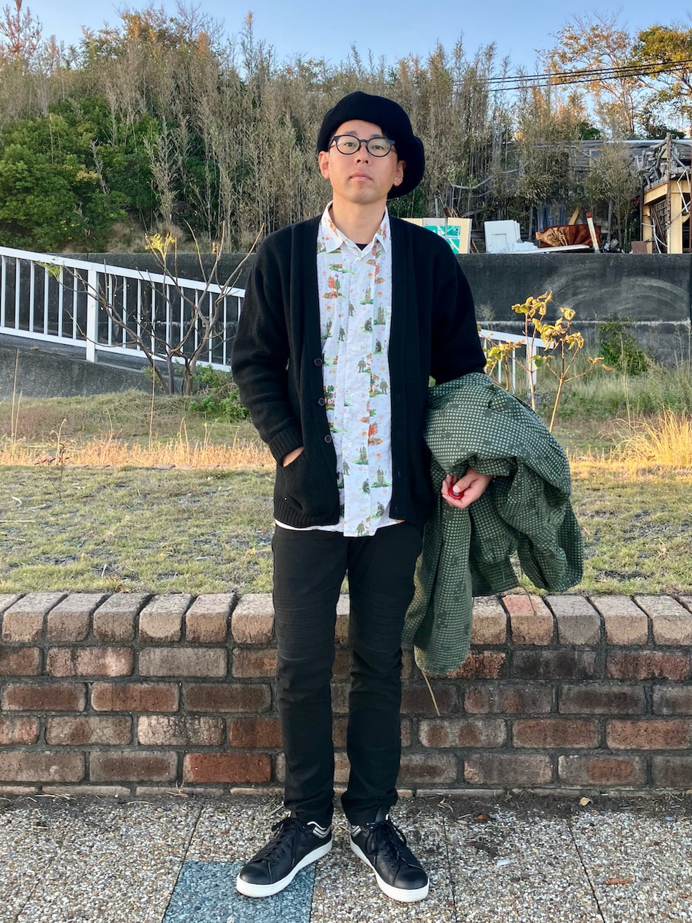 グリーン系のミリタリージャケット、ブラック系のパンツ、ブラック系のスニーカーを着用したメンズの秋コーディネートの2枚目の写真