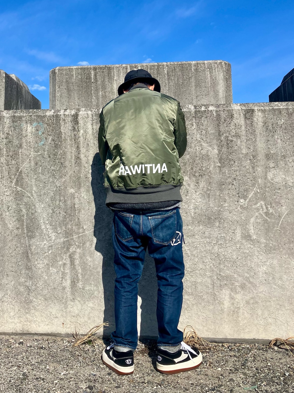 ブラック系のスニーカー、グレー系のニット/セーター、グリーン系のMA-1を着用したメンズの冬コーディネートの2枚目の写真