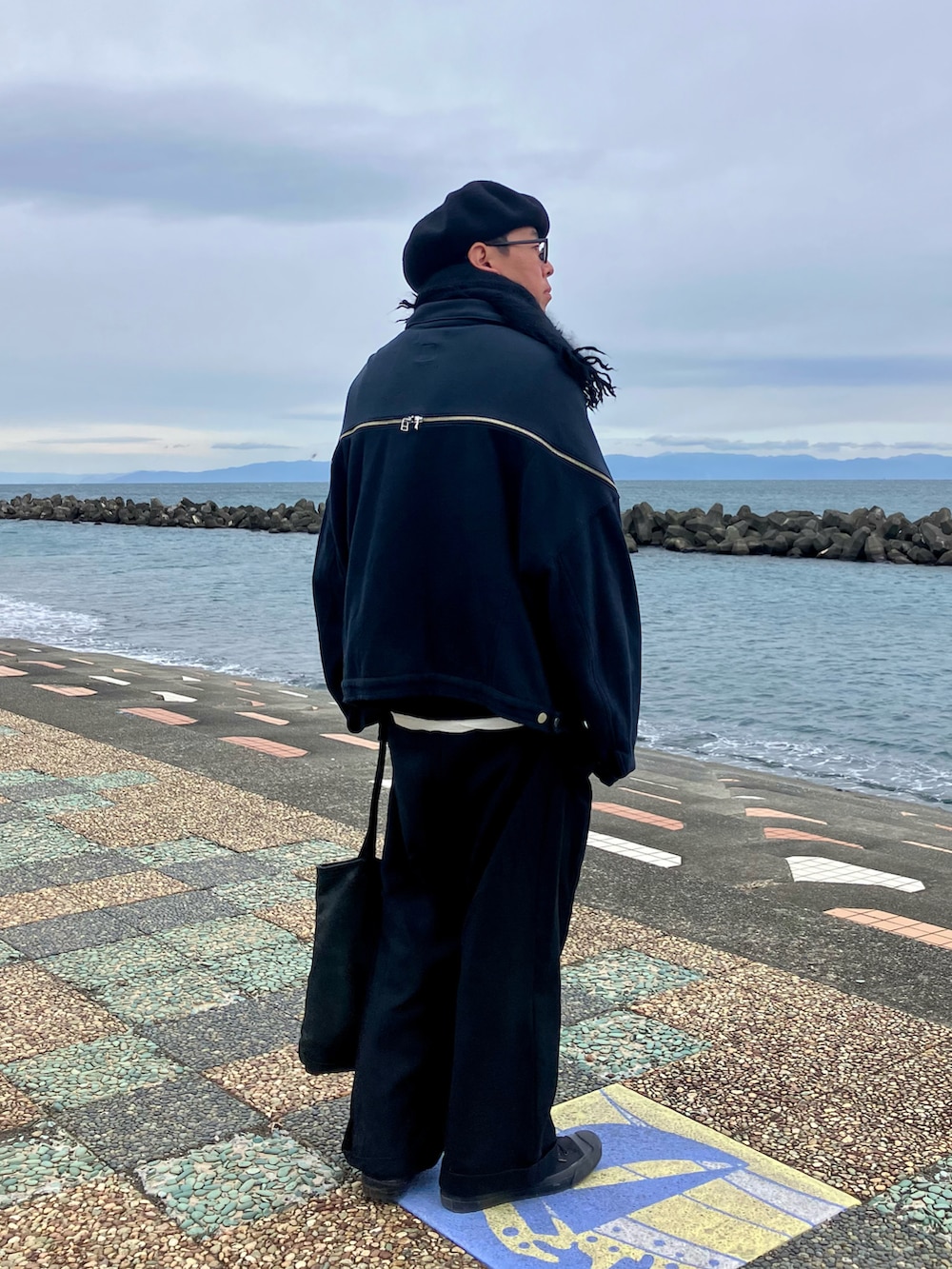 ブラック系のジャケット/アウター、ブラック系のその他パンツ、ブラック系のトートバッグを着用したメンズの冬コーディネートの2枚目の写真