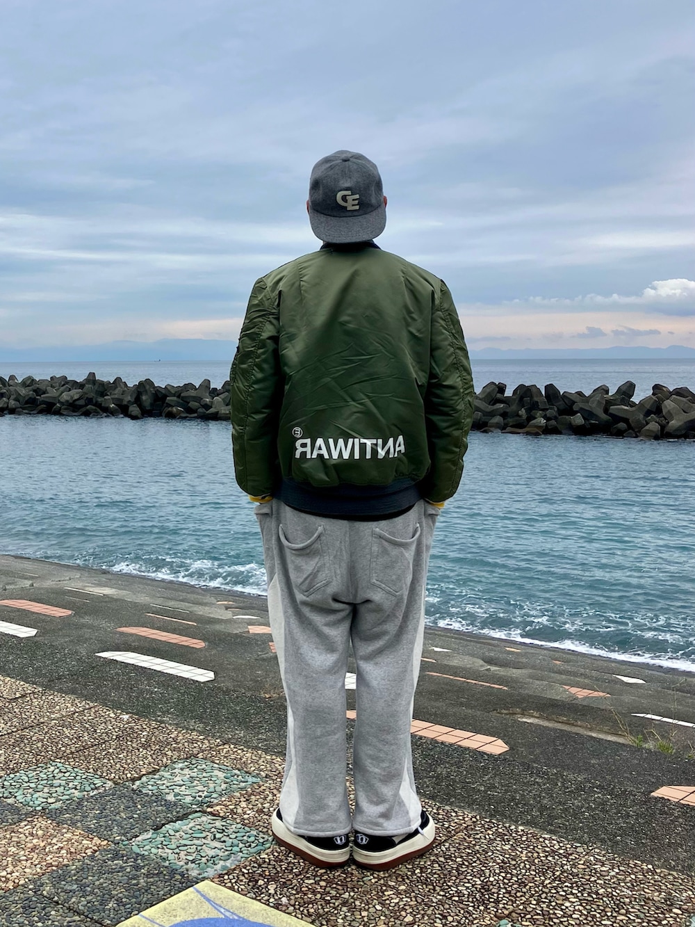 ブラック系のスニーカー、ブラック系のニット/セーター、グリーン系のMA-1を着用したメンズの秋コーディネートの2枚目の写真