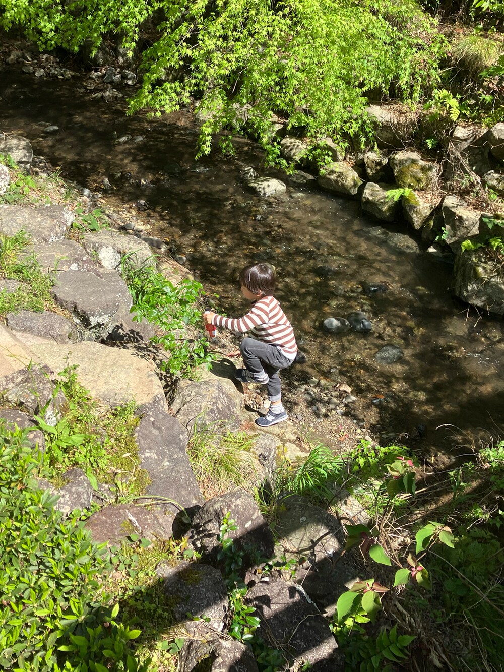 グレー系のスウェット、ブルー系のデニムパンツ、ブラック系のスニーカーを着用したメンズの春コーディネートの2枚目の写真