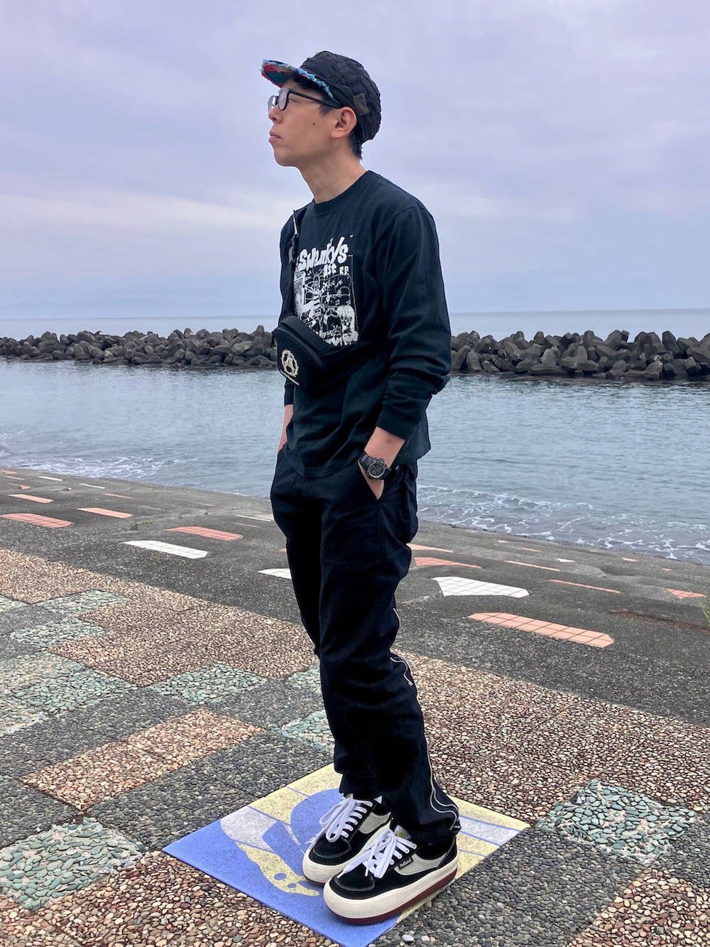 ブラック系のスニーカー、ブラック系のTシャツ/カットソー、ブラック系のパンツを着用したメンズの春コーディネートの2枚目の写真