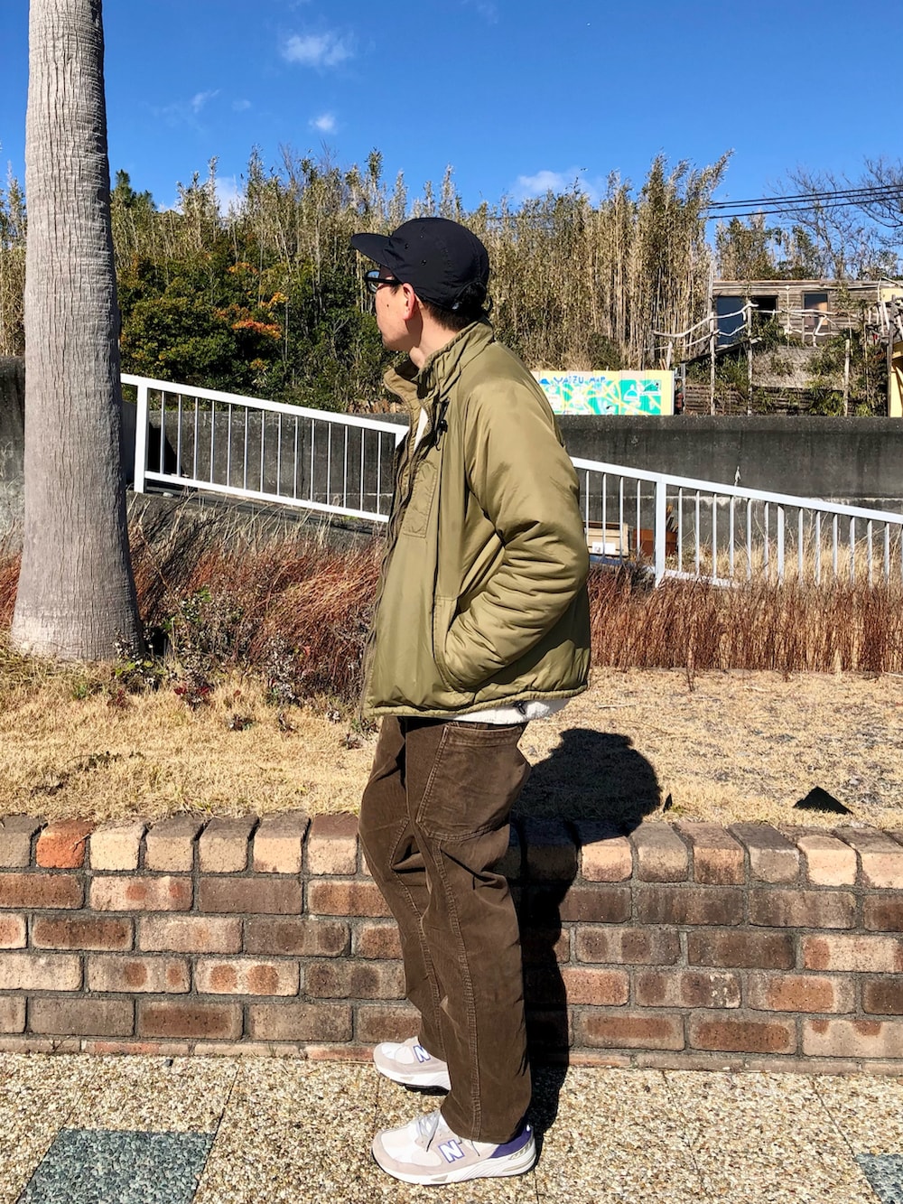 ホワイト系のTシャツ/カットソー、グリーン系のミリタリージャケット、ブラウン系のパンツを着用したメンズの冬コーディネートの2枚目の写真