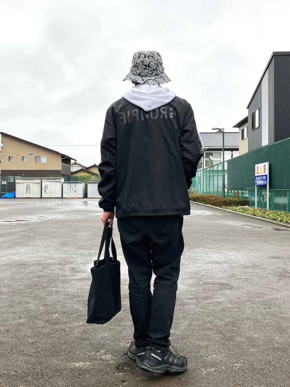 ホワイト系のパーカー、ブラック系のブルゾン、ブラック系のエコバッグ/サブバッグを着用したメンズの春コーディネートの3枚目の写真