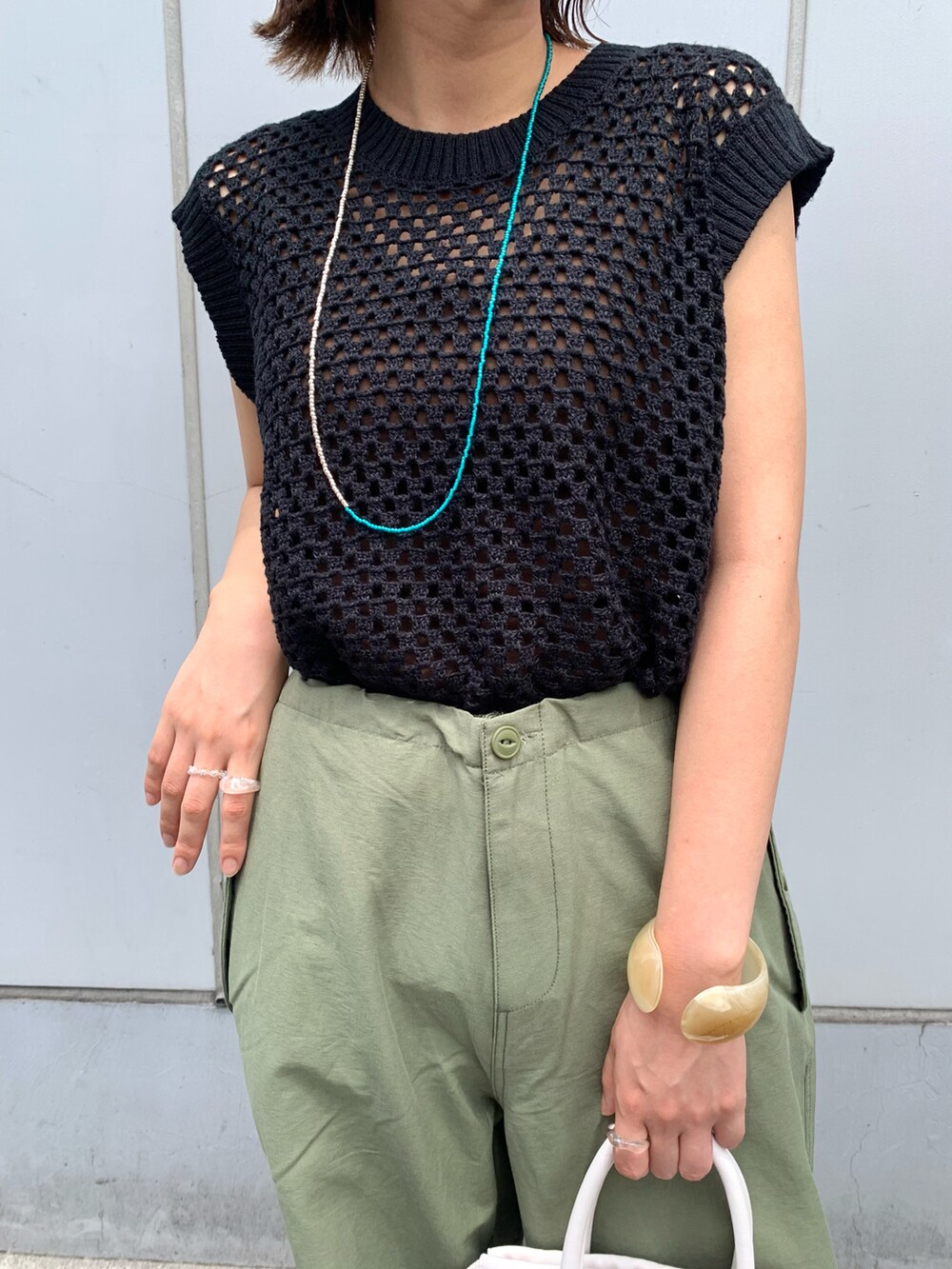 グリーン系のその他パンツ、ホワイト系のショルダーバッグ、ブラック系のニット/セーターを着用したレディースの夏コーディネートの3枚目の写真