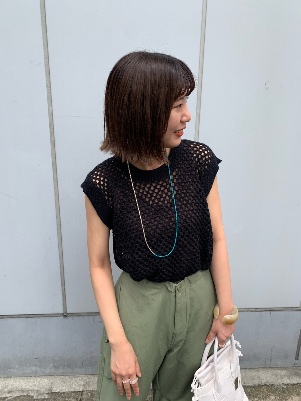 グリーン系のその他パンツ、ホワイト系のショルダーバッグ、ブラック系のニット/セーターを着用したレディースの夏コーディネートの2枚目の写真