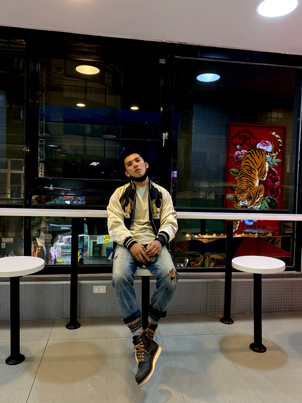 ベージュ系のスカジャン、ブルー系のデニムパンツ、ブルー系のブーツを着用したメンズの秋コーディネートの2枚目の写真