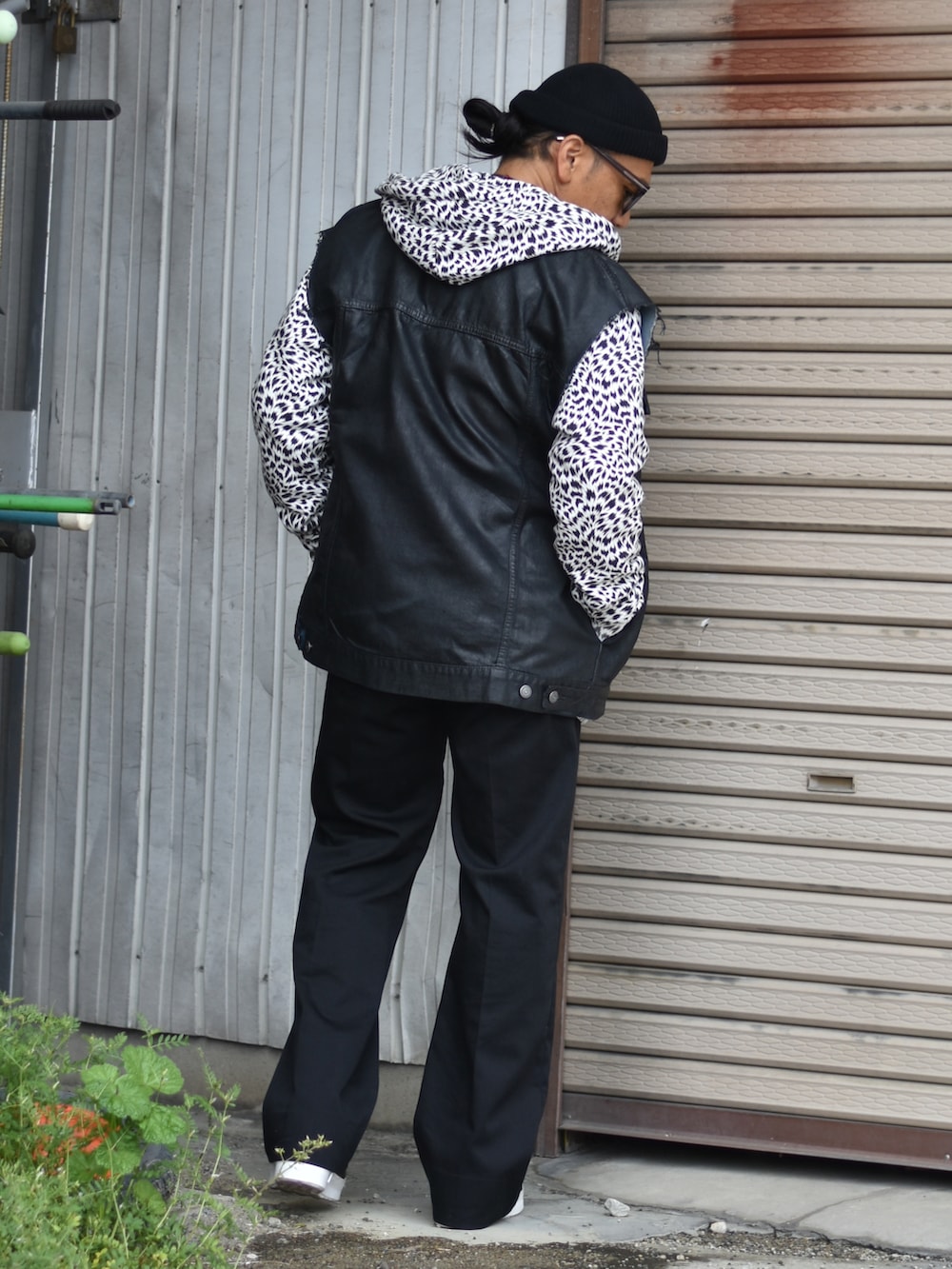 ホワイト系のパーカー、ブラック系のベスト、ブラック系のチノパンツを着用したメンズの春コーディネートの2枚目の写真