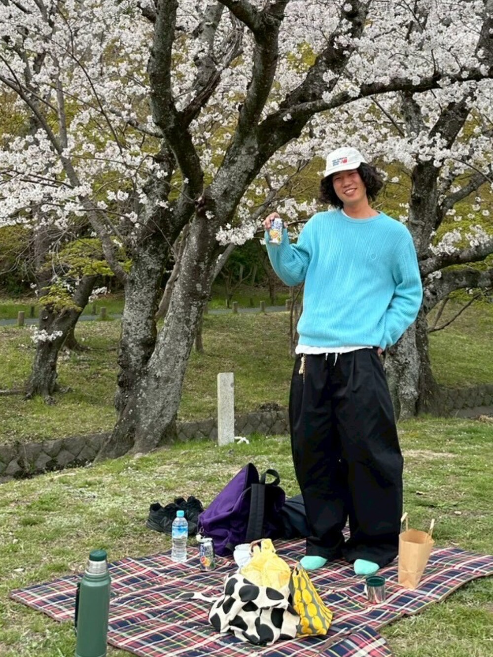 ブルー系のトレンチコート、グレー系のパンツ、ブラック系のスニーカーを着用したメンズの春コーディネートの2枚目の写真