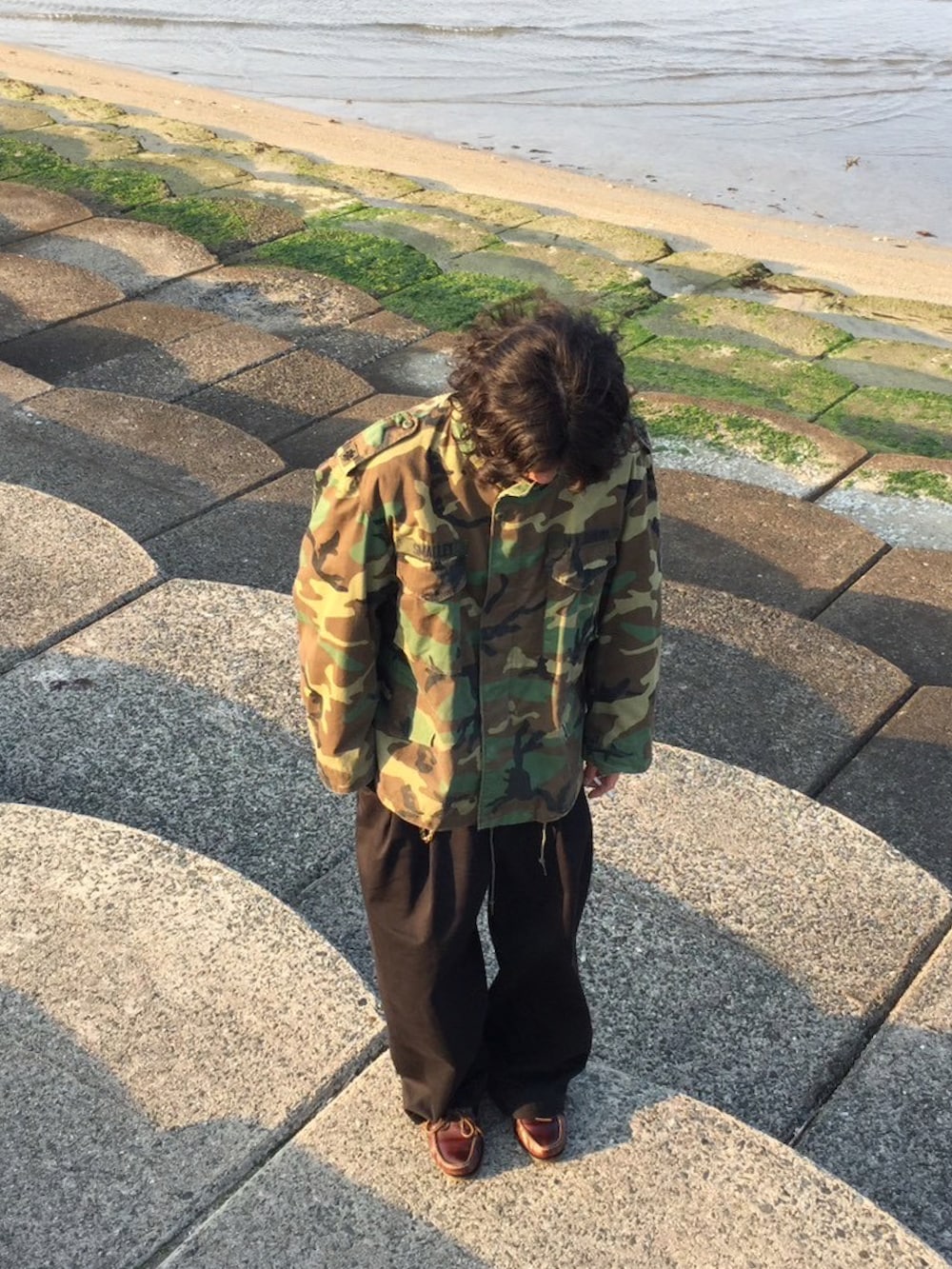 グリーン系のミリタリージャケット、ブラウン系のローファーを着用したメンズの冬コーディネートの2枚目の写真