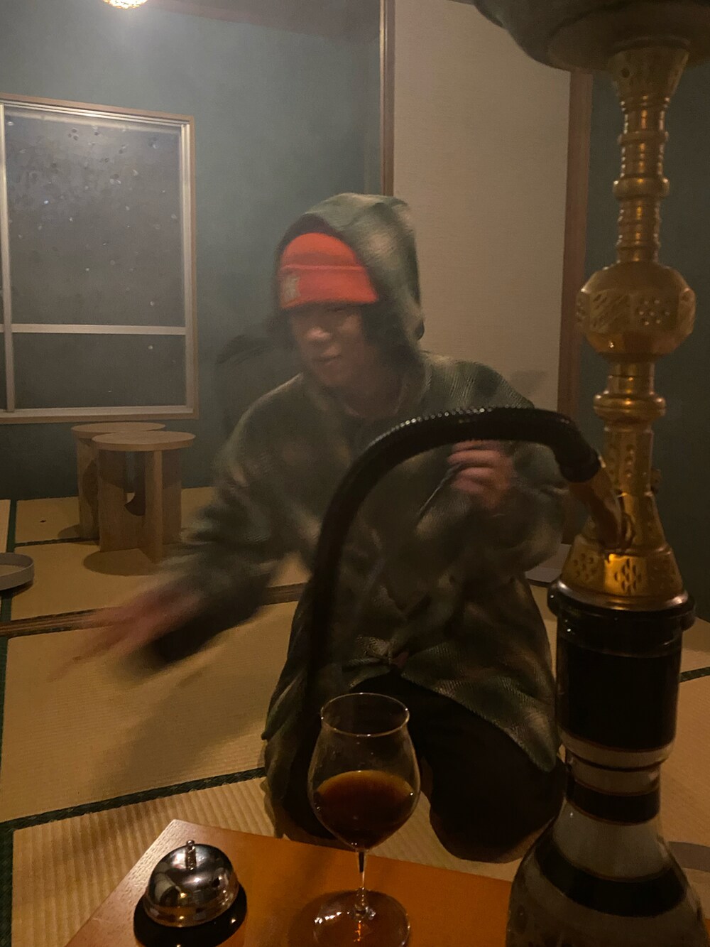 グリーン系のダッフルコート、ブラウン系のスラックス、オレンジ系のニットキャップ/ビーニーを着用したメンズの秋コーディネートの2枚目の写真