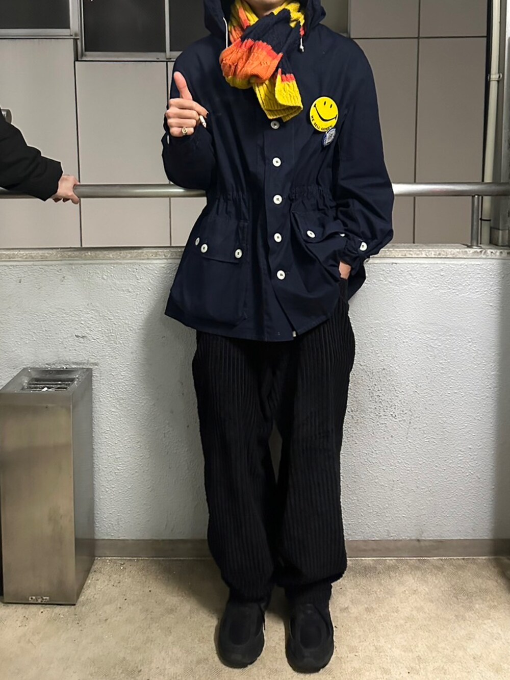 ブルー系のミリタリージャケット、ブラック系のパンツ、ブラック系のスニーカーを着用したメンズの春コーディネートの2枚目の写真