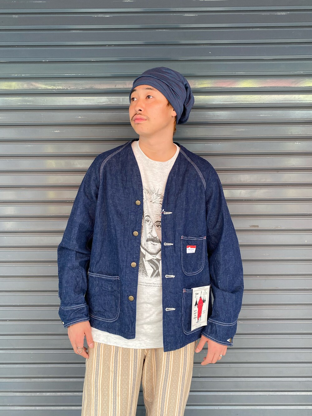 ブラック系のサンダル、ブルー系のデニムジャケット、ベージュ系のTシャツ/カットソーを着用したメンズの夏コーディネートの2枚目の写真