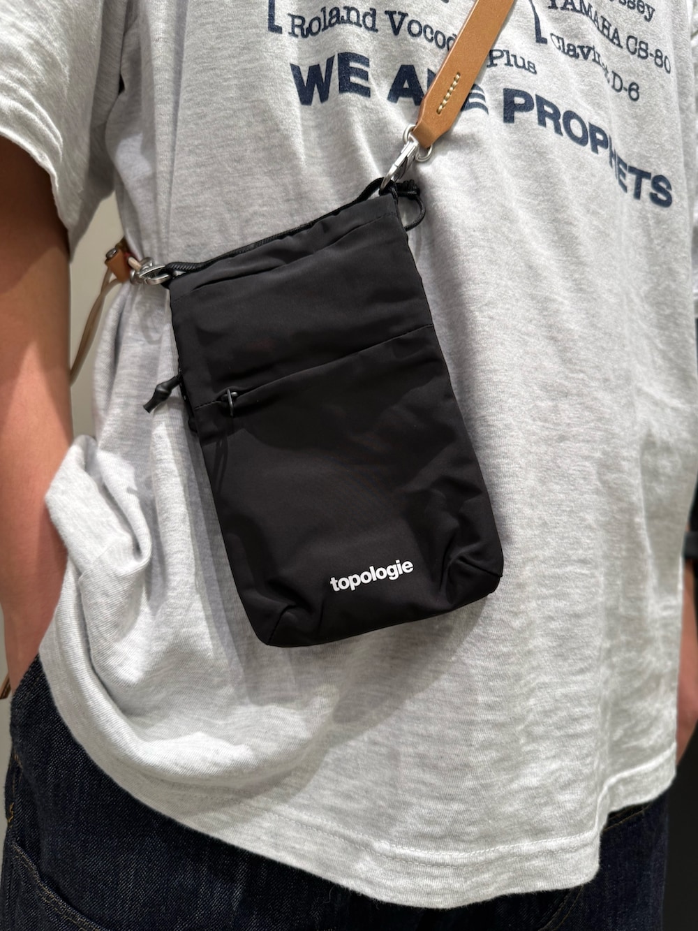 ブラック系のショルダーバッグ、ベージュ系のスマホグッズを着用したメンズの夏コーディネートの3枚目の写真