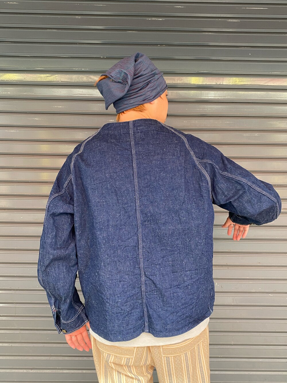 ブラック系のサンダル、ブルー系のデニムジャケット、ベージュ系のTシャツ/カットソーを着用したメンズの夏コーディネートの3枚目の写真