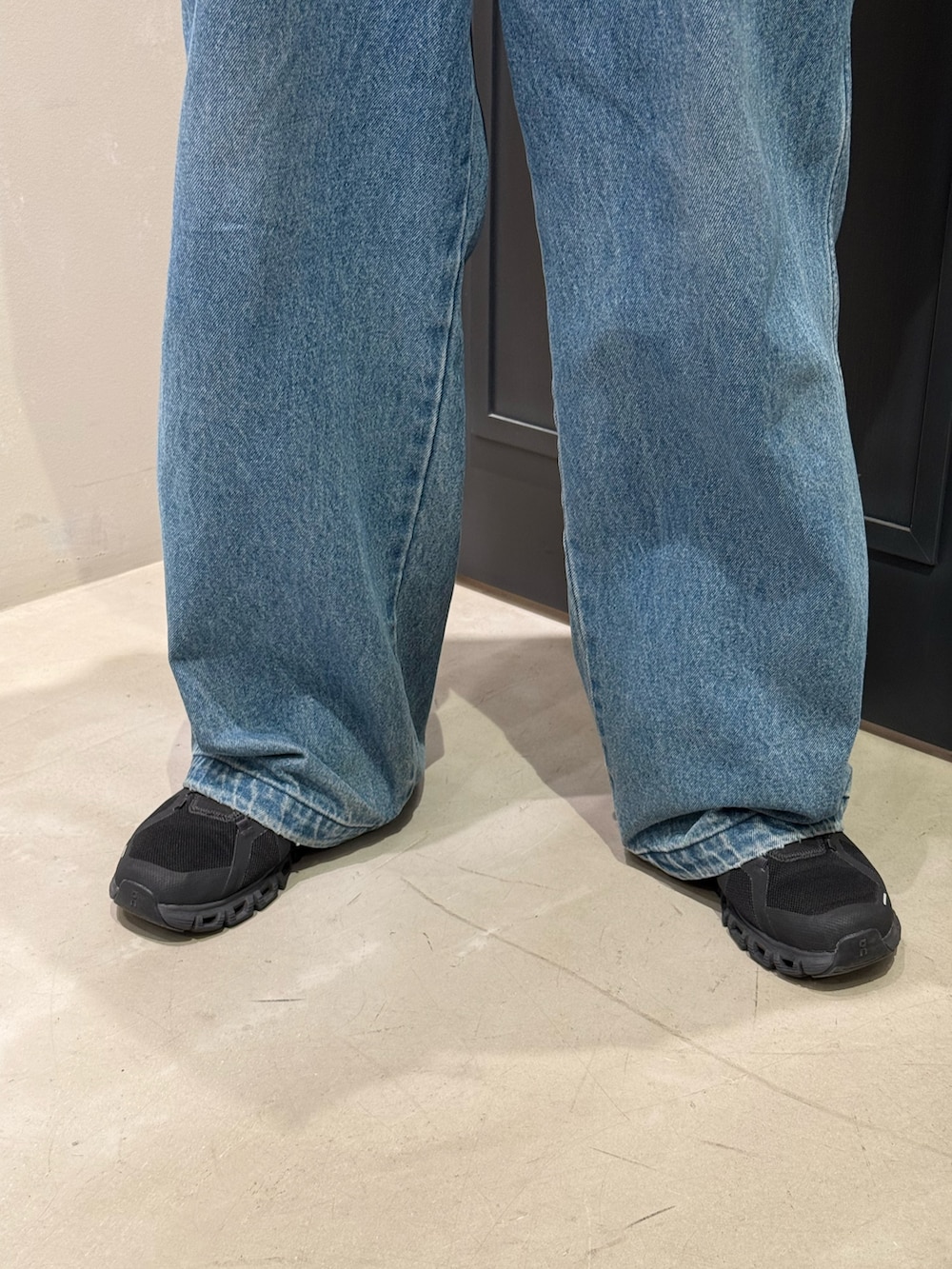 ブルー系のデニムパンツ、ブラック系のスニーカー、ブラック系のショルダーバッグを着用したメンズの秋コーディネートの6枚目の写真