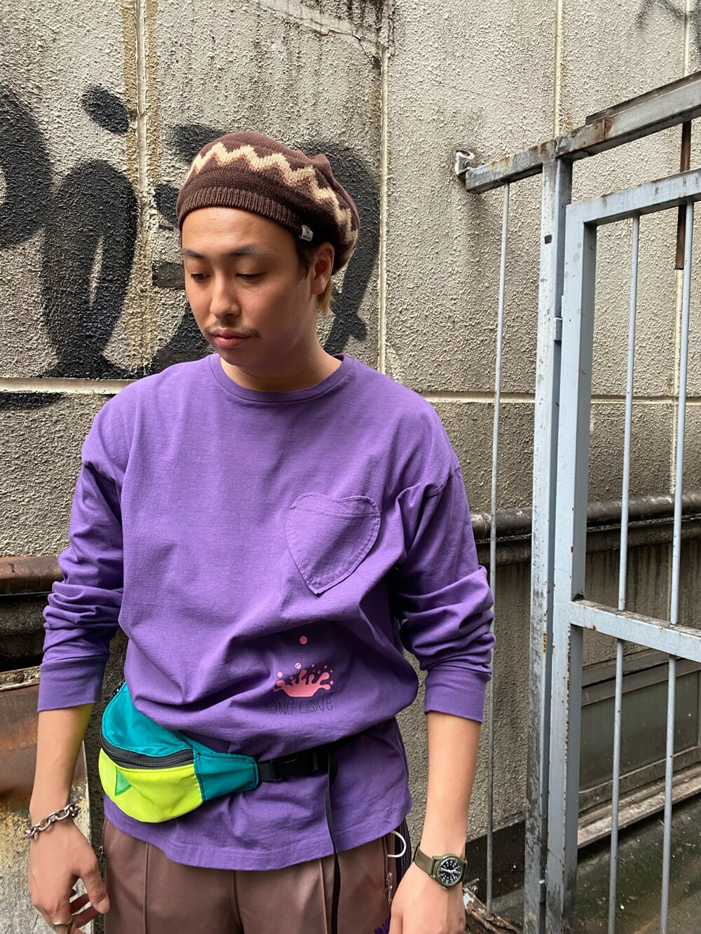 パープル系のTシャツ/カットソー、ベージュ系のパンツ、ブラック系のサンダルを着用したメンズの夏コーディネートの2枚目の写真