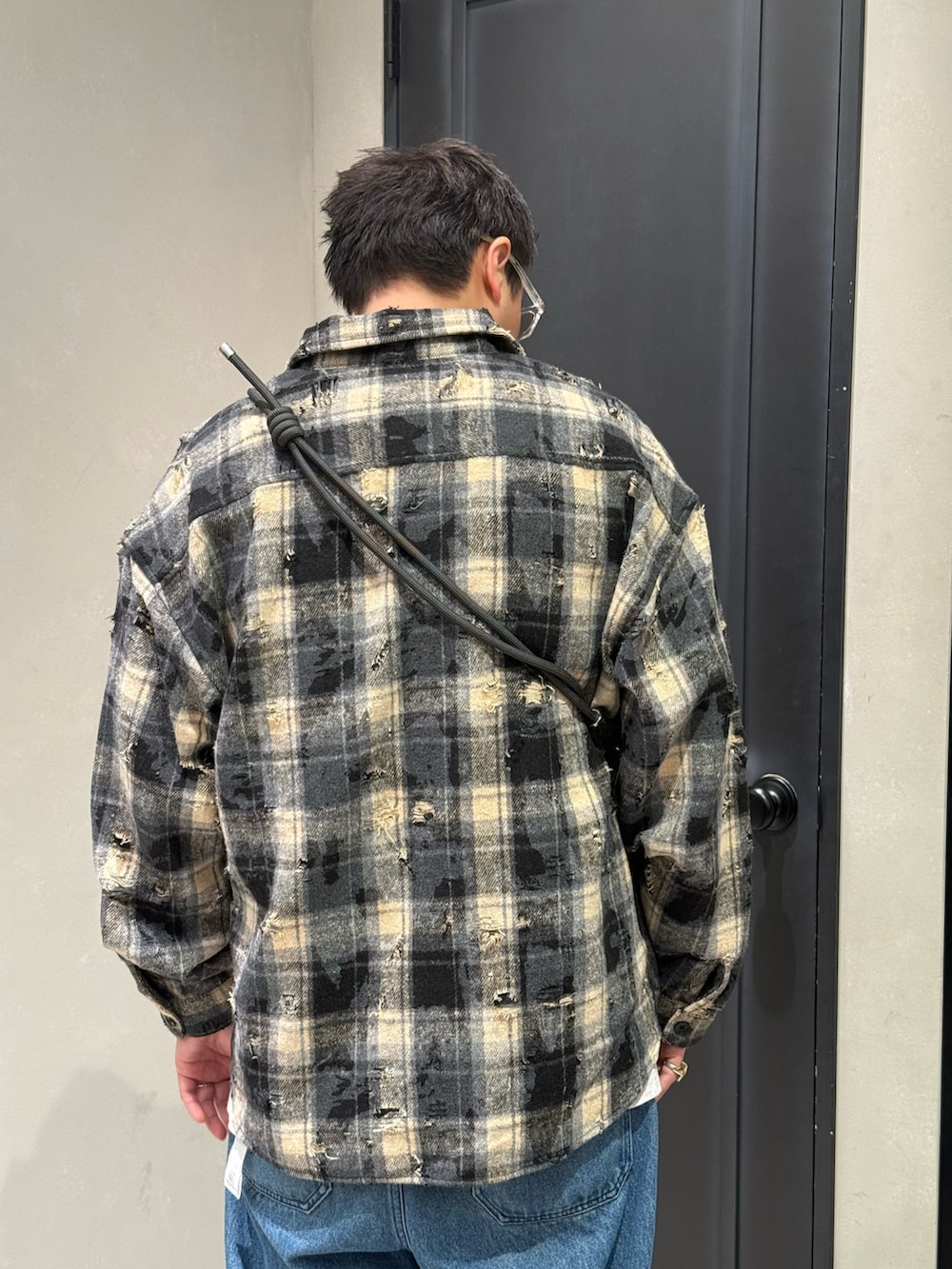 ブルー系のデニムパンツ、ブラック系のスニーカー、ブラック系のショルダーバッグを着用したメンズの秋コーディネートの8枚目の写真