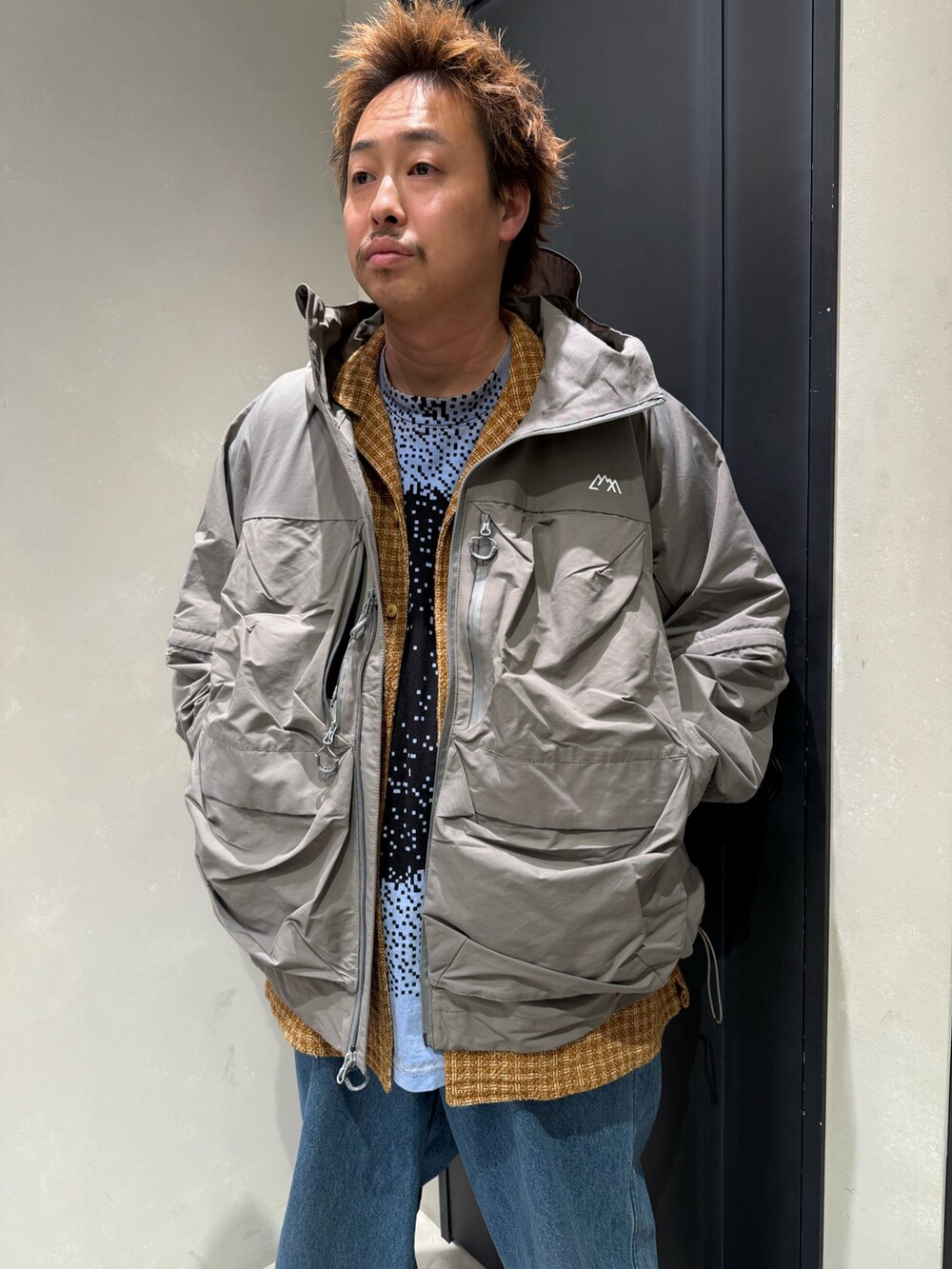 グレー系のマウンテンパーカー、ブルー系のデニムパンツを着用したメンズの秋コーディネートの2枚目の写真