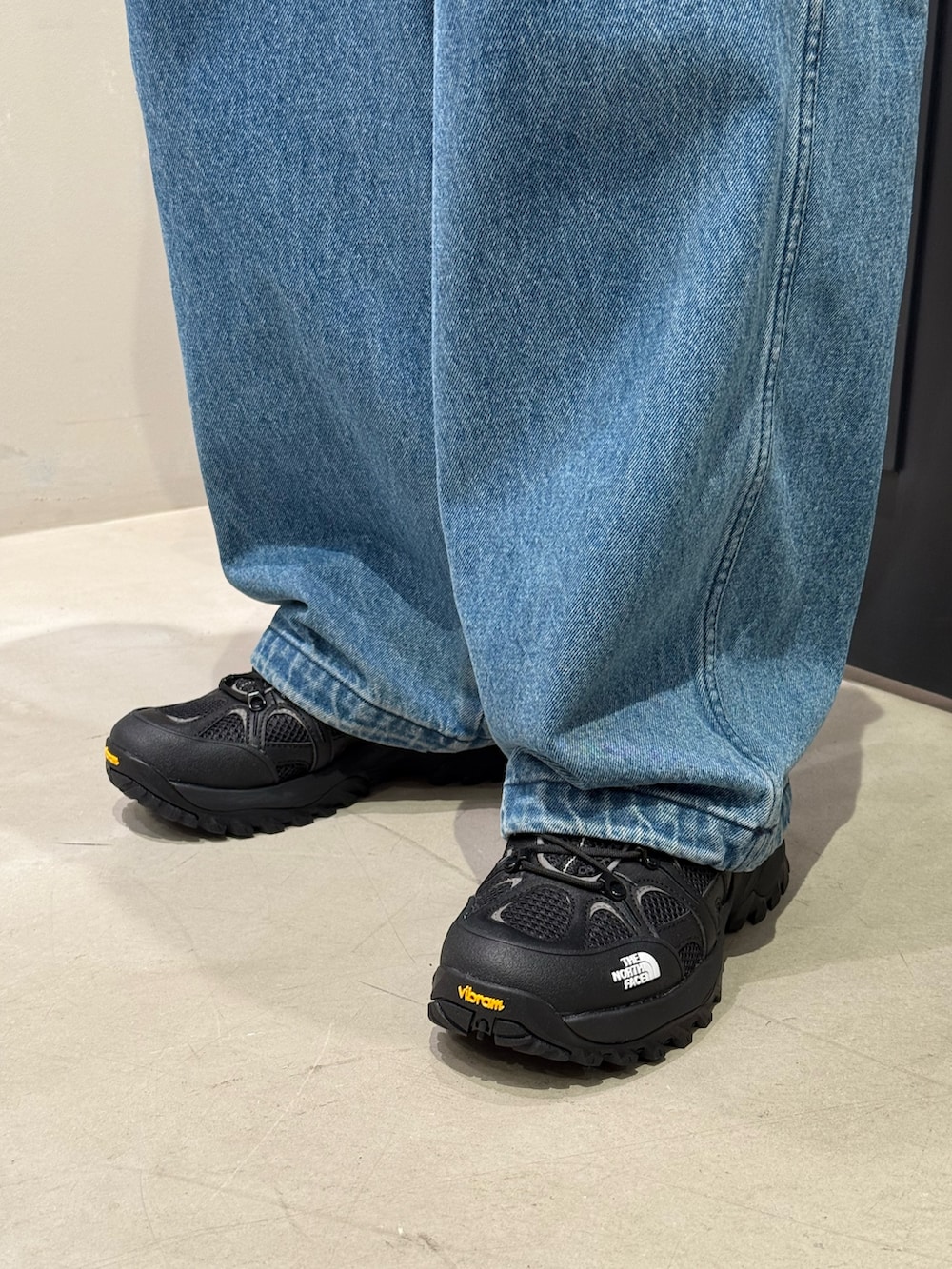 ブラック系のスニーカー、ブルー系のデニムパンツを着用したメンズの春コーディネートの4枚目の写真