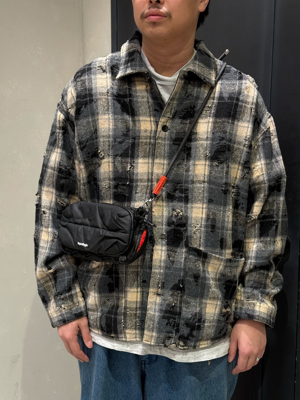 ブルー系のデニムパンツ、ブラック系のスニーカー、ブラック系のショルダーバッグを着用したメンズの秋コーディネートの2枚目の写真