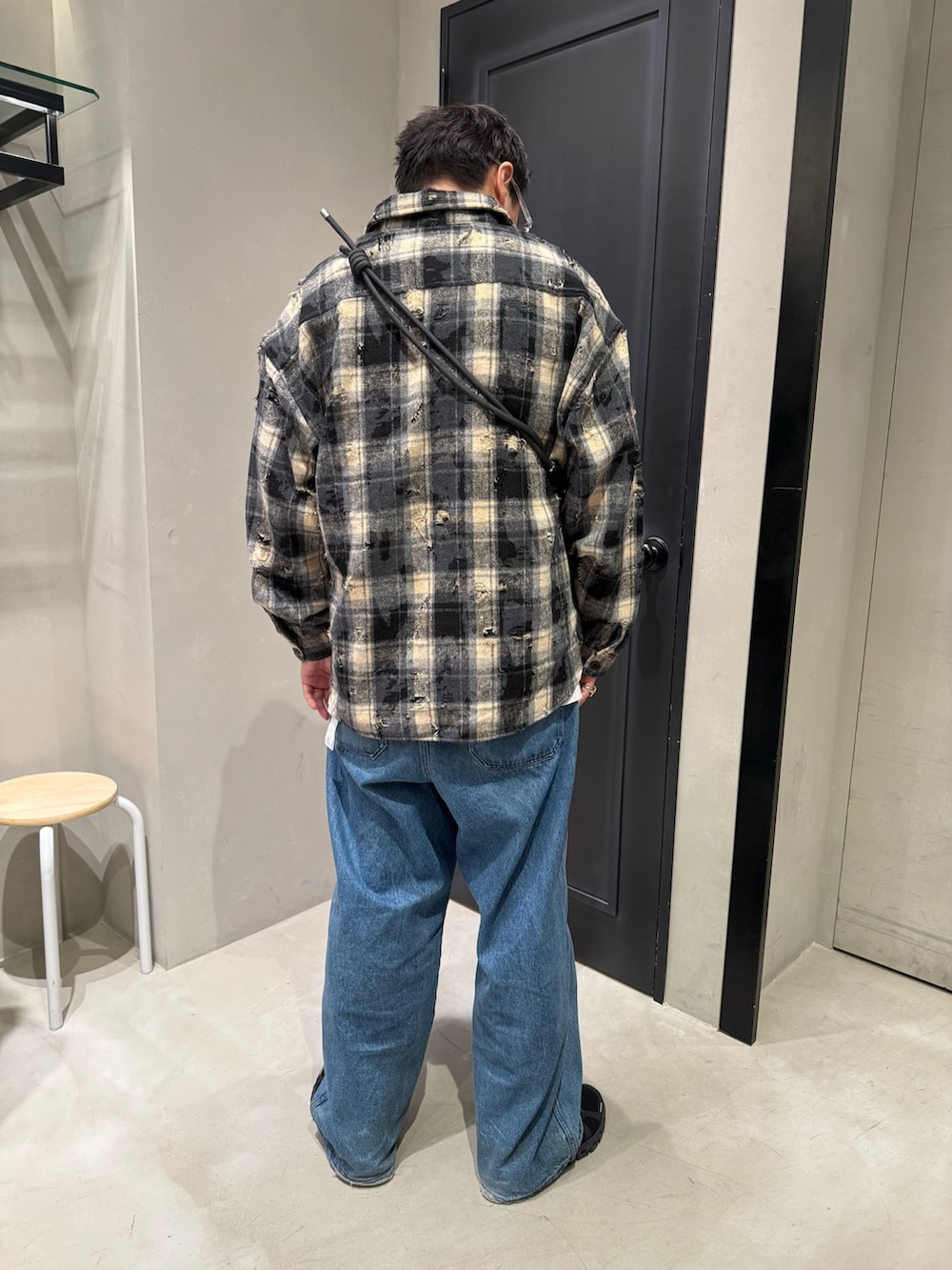 ブルー系のデニムパンツ、ブラック系のスニーカー、ブラック系のショルダーバッグを着用したメンズの秋コーディネートの7枚目の写真