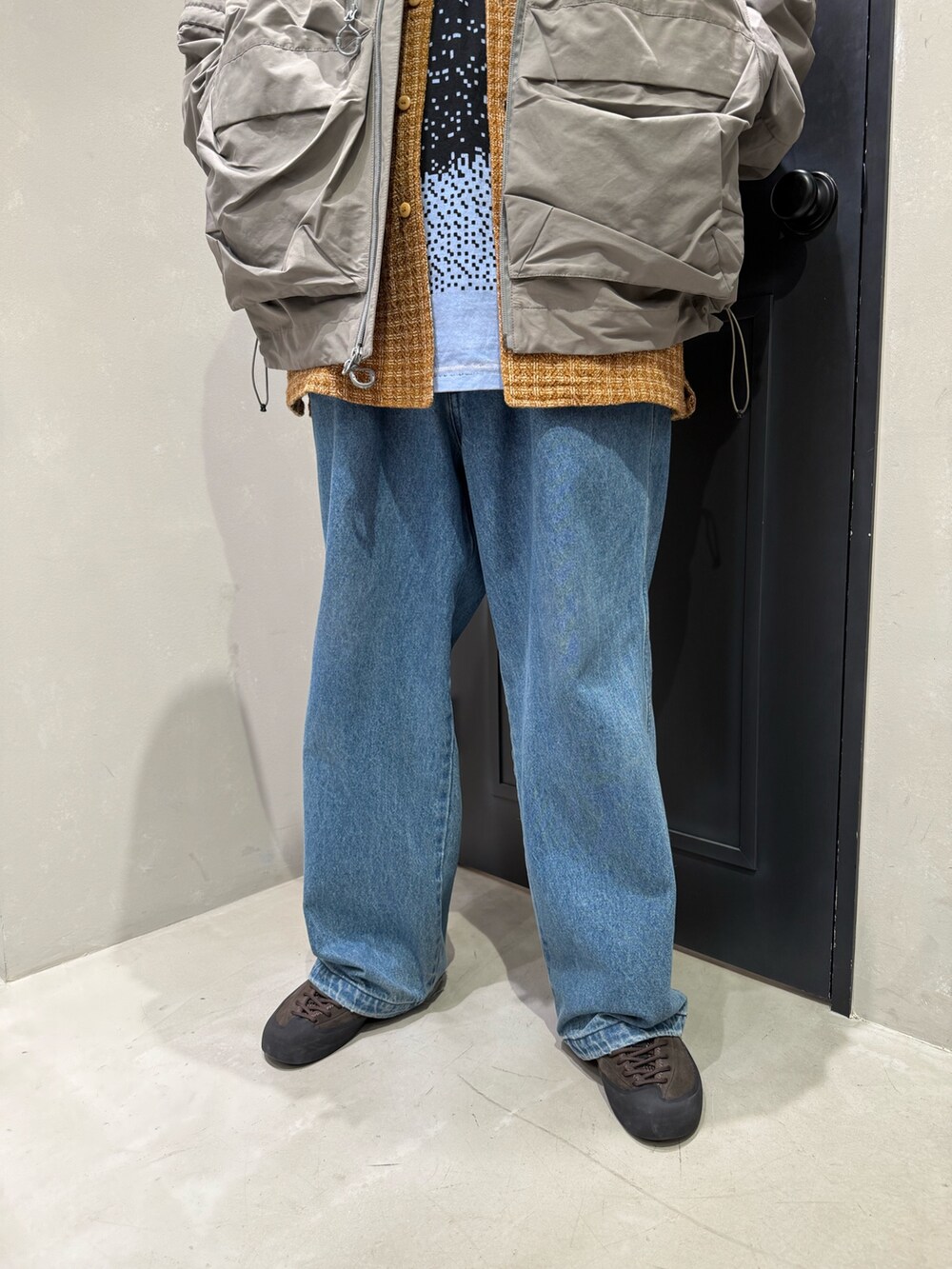 グレー系のマウンテンパーカー、ブルー系のデニムパンツを着用したメンズの秋コーディネートの3枚目の写真