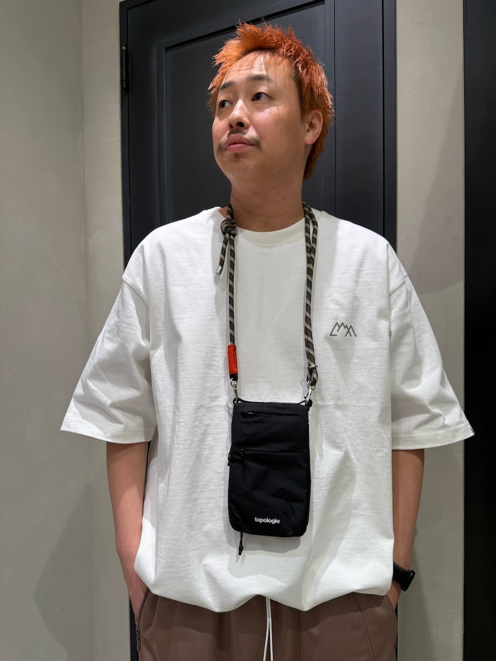 ブラック系のショルダーバッグ、ブラック系のスニーカー、ホワイト系のTシャツ/カットソーを着用したメンズの春コーディネートの2枚目の写真