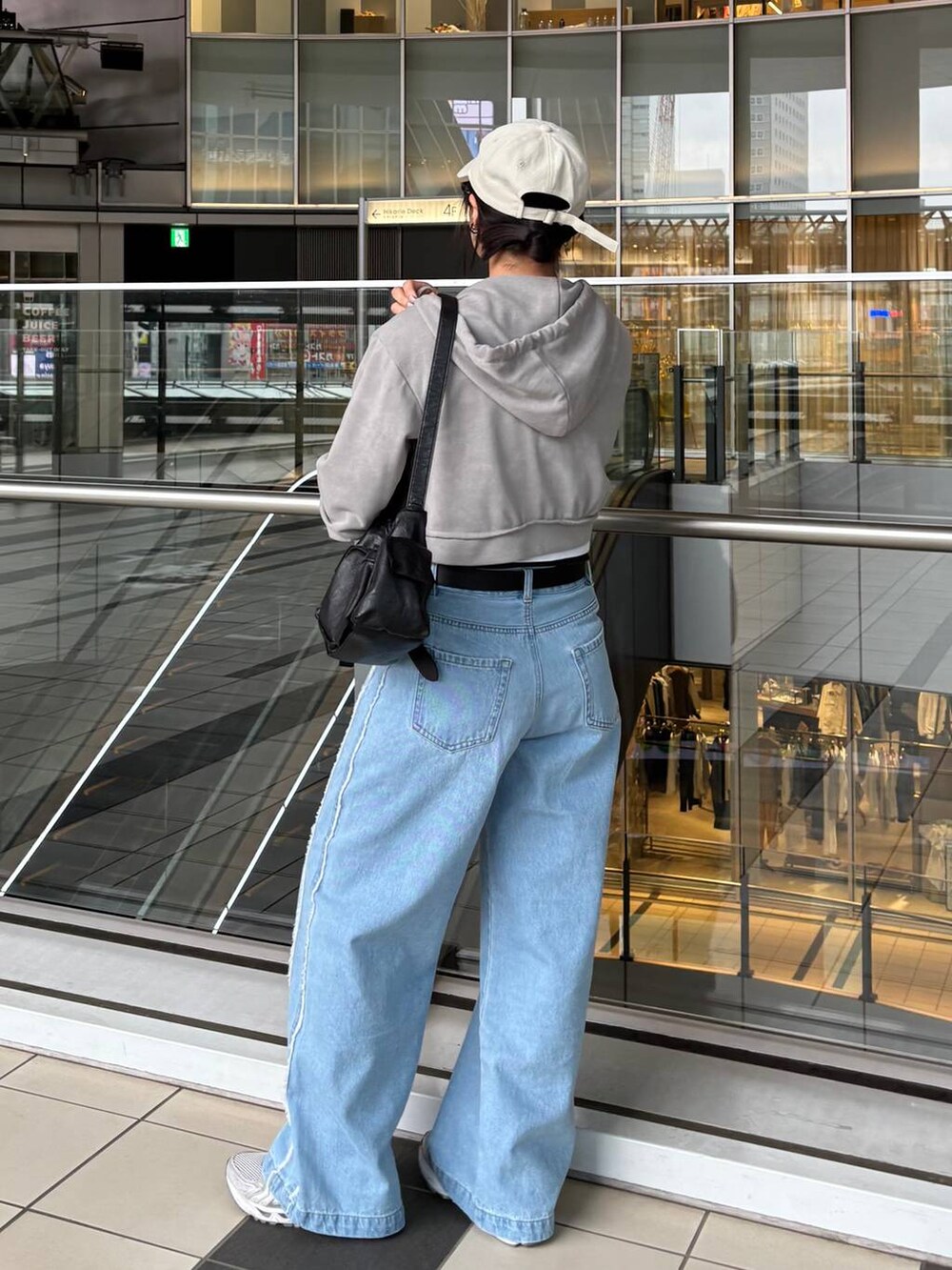 ブラック系のショルダーバッグ、ブルー系のデニムパンツ、ホワイト系のハットを着用したレディースの春コーディネートの3枚目の写真