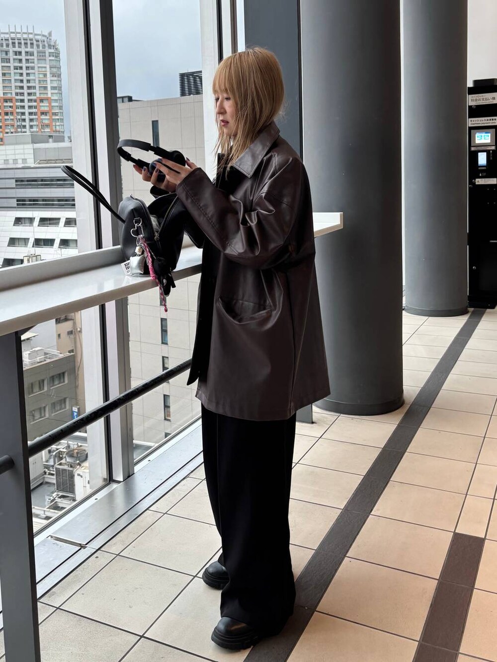 ブラウン系のステンカラーコート、ブラック系のボストンバッグを着用したレディースの秋コーディネートの6枚目の写真