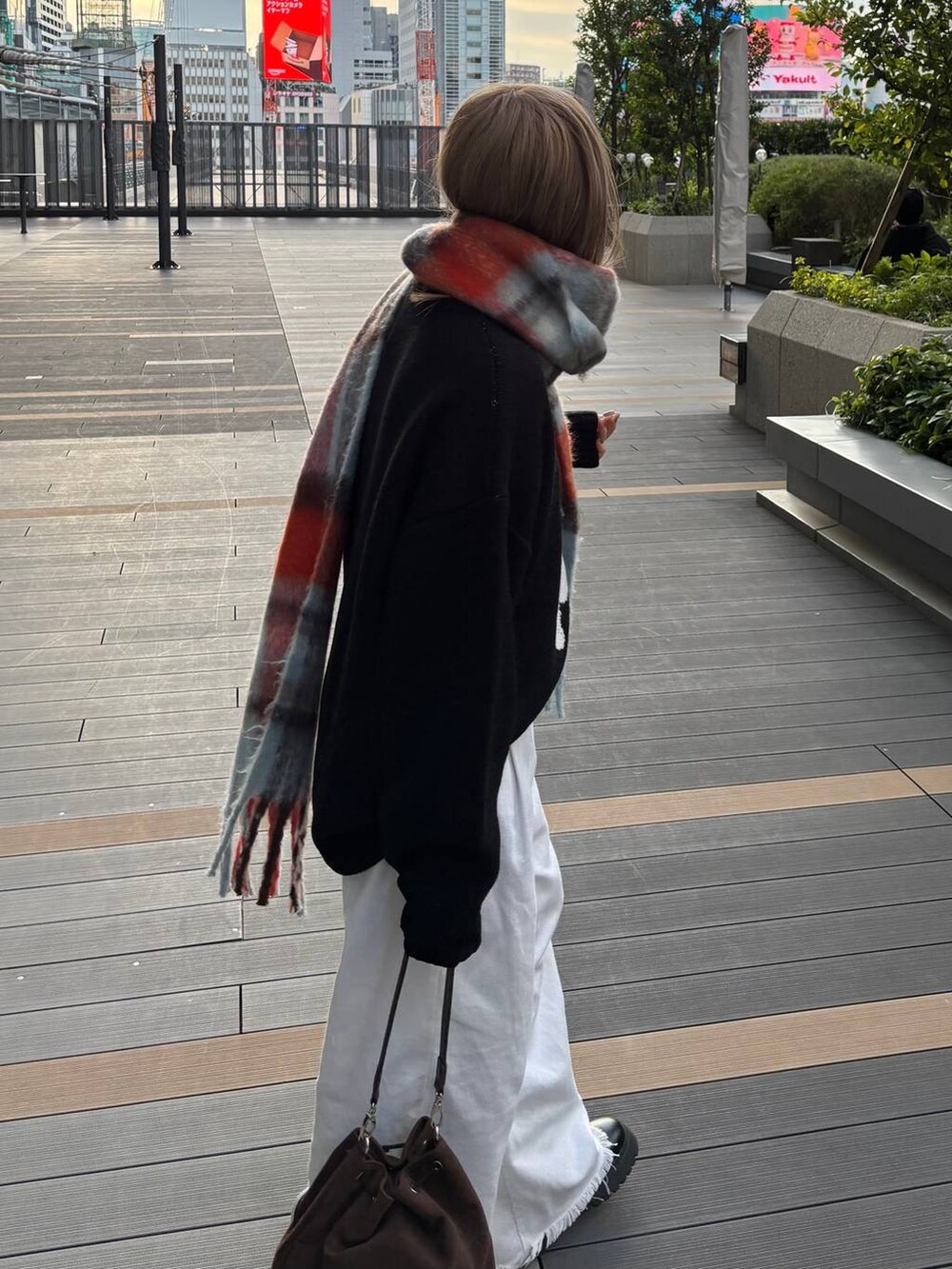 ブラウン系のショルダーバッグ、ブラック系のニット/セーター、ブルー系のマフラーを着用したレディースの秋コーディネートの2枚目の写真