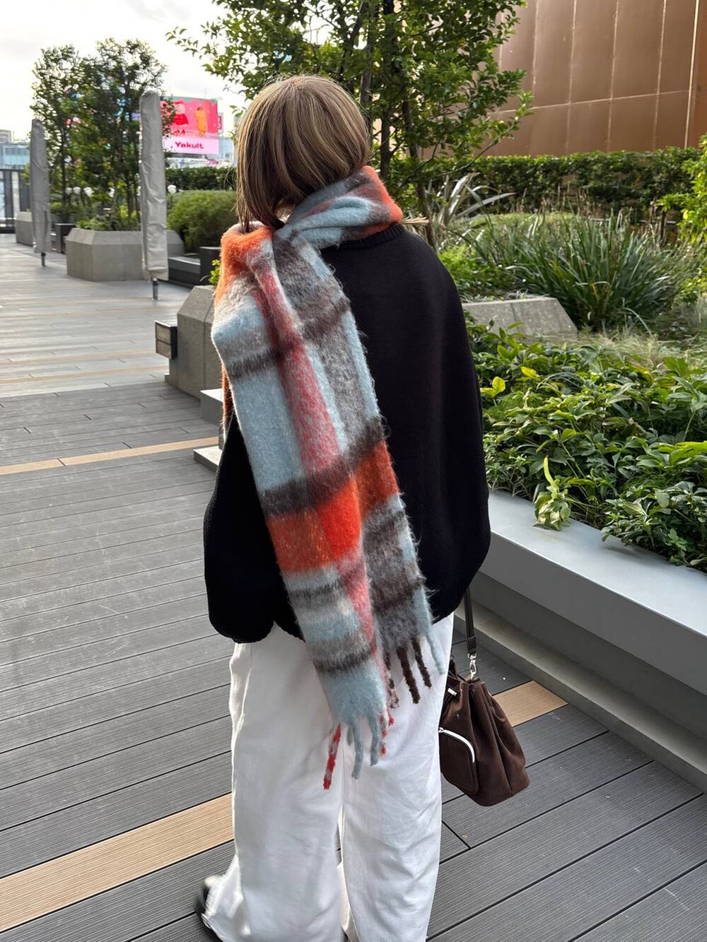 ブラウン系のショルダーバッグ、ブラック系のニット/セーター、ブルー系のマフラーを着用したレディースの秋コーディネートの6枚目の写真