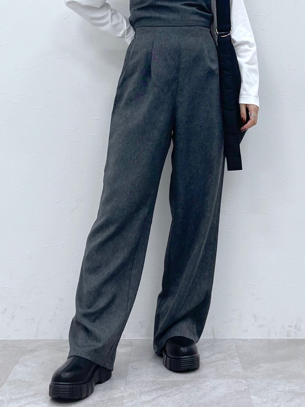 ホワイト系のトップス、ブラック系のサロペット/オーバーオール、ブラック系のブーツを着用したレディースの秋コーディネートの6枚目の写真