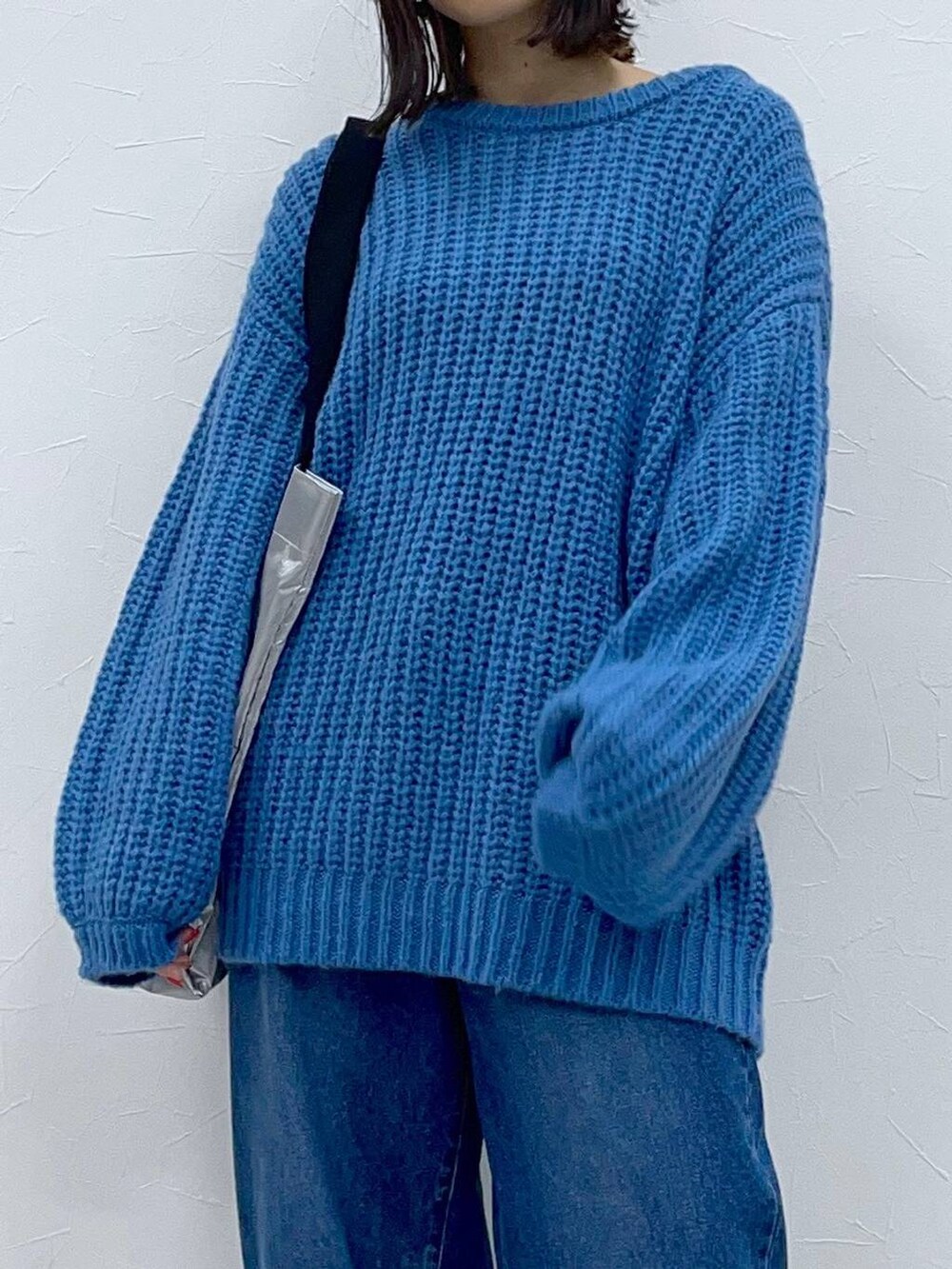 ブラック系のブーツ、ブルー系のデニムパンツ、シルバー系のトートバッグを着用したレディースの秋コーディネートの6枚目の写真