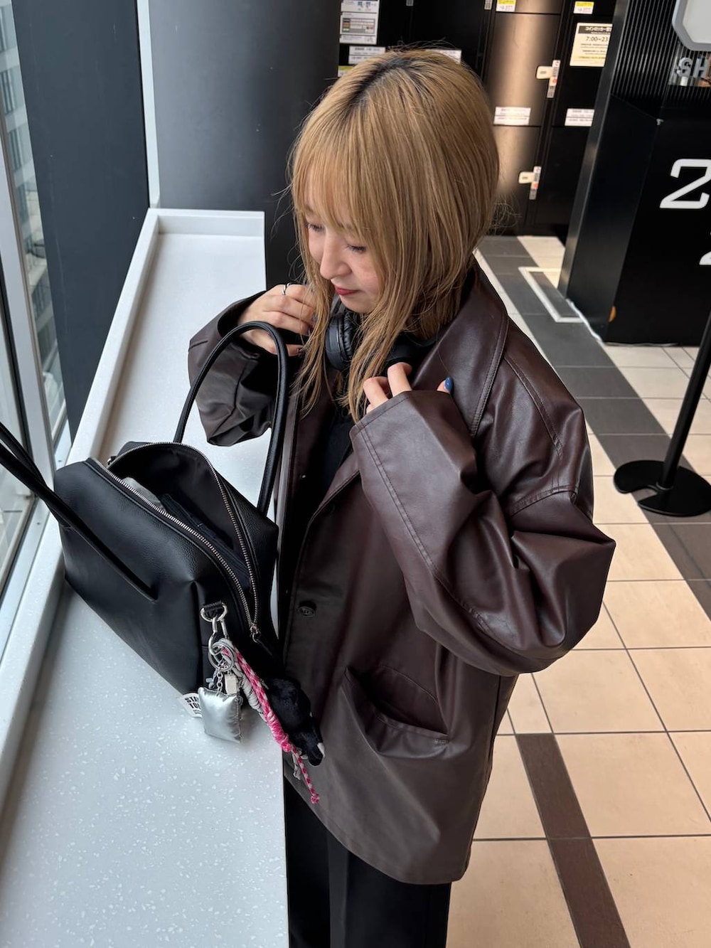 ブラウン系のステンカラーコート、ブラック系のボストンバッグを着用したレディースの秋コーディネートの3枚目の写真