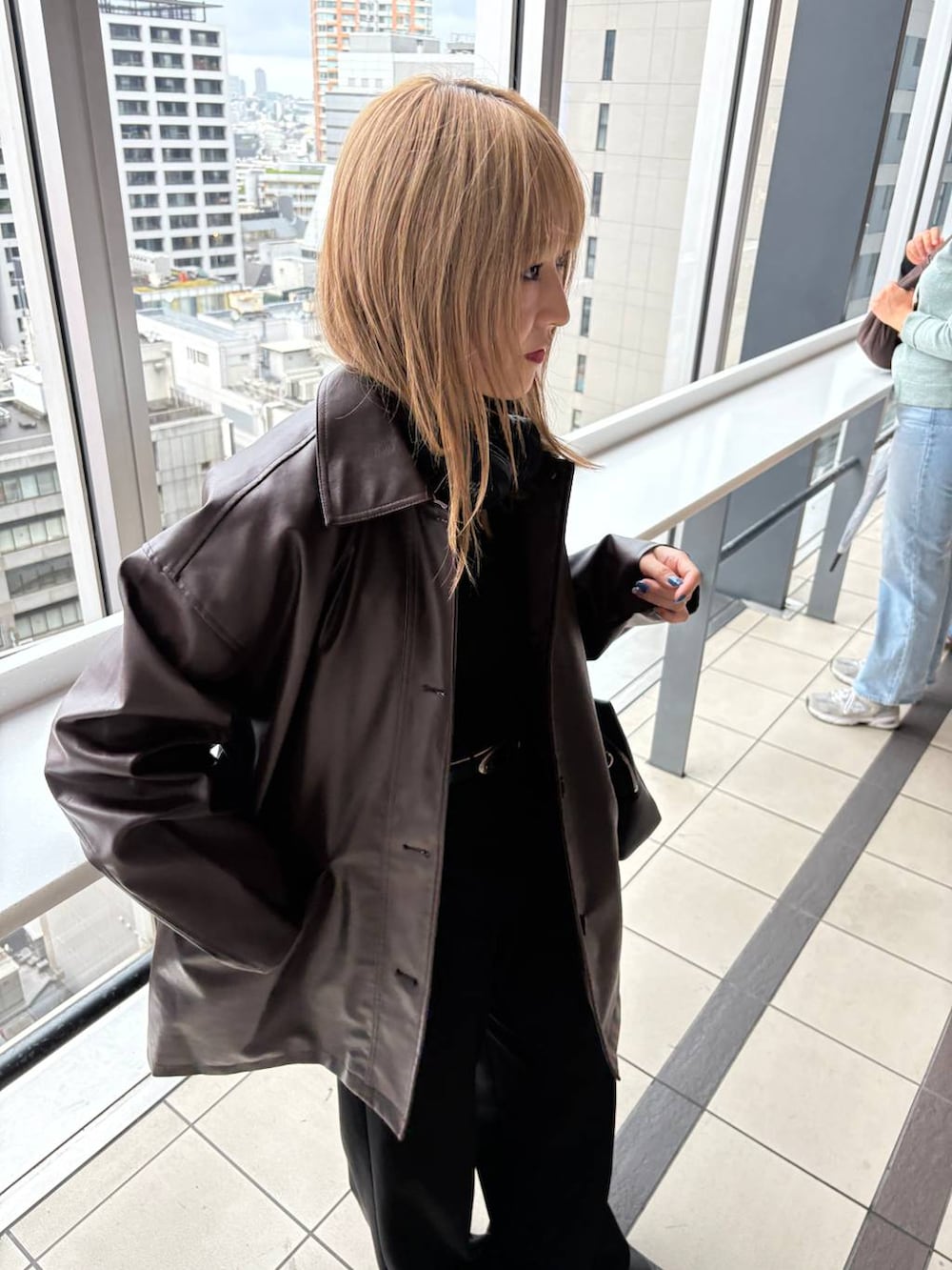 ブラウン系のステンカラーコート、ブラック系のボストンバッグを着用したレディースの秋コーディネートの4枚目の写真