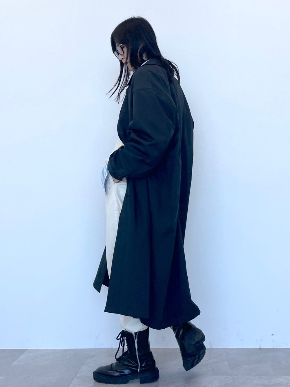 ブラック系のステンカラーコート、ベージュ系のニット/セーター、ブルー系のシャツ/ブラウスを着用したレディースの冬コーディネートの3枚目の写真