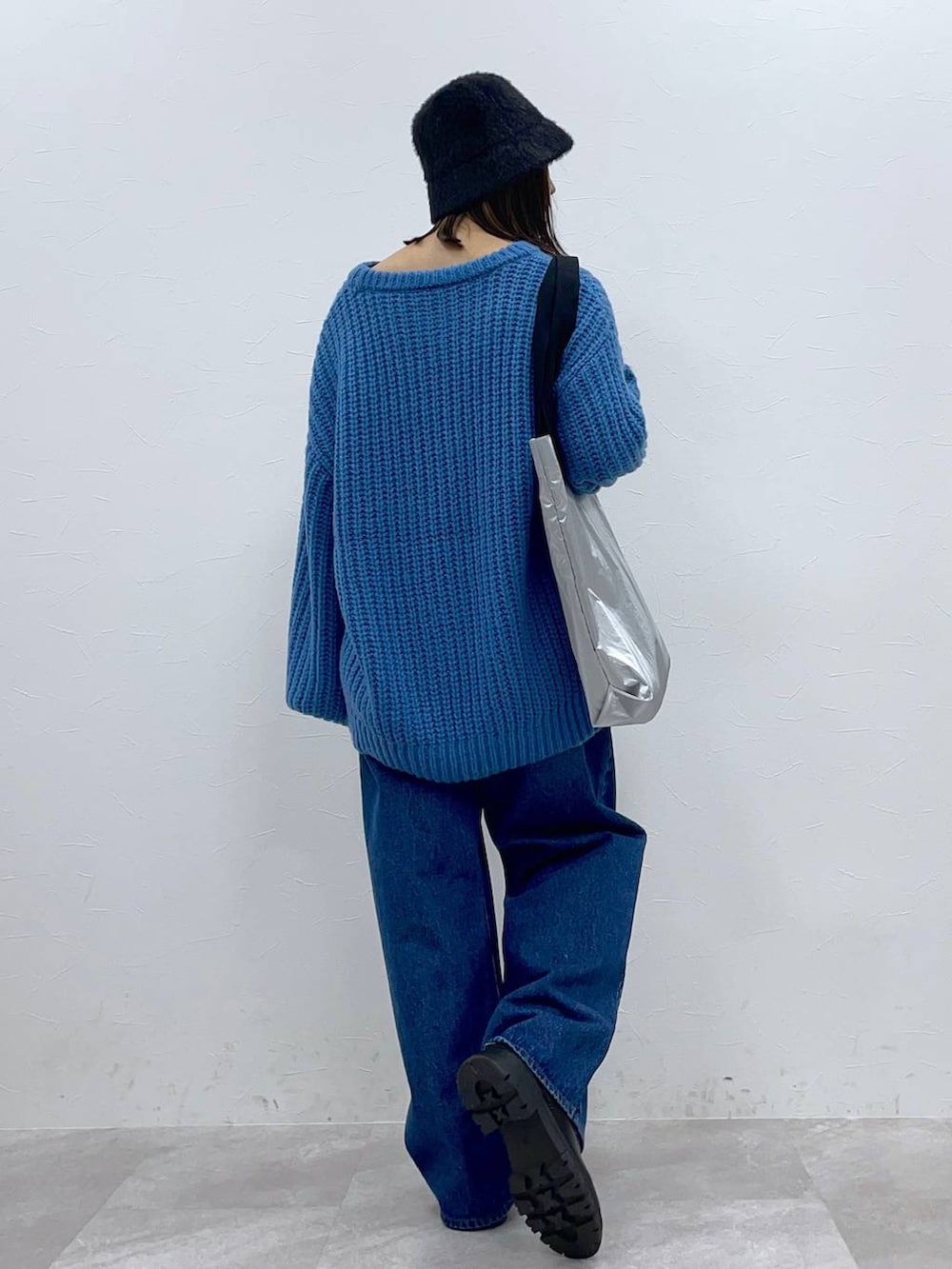 ブラック系のブーツ、ブルー系のデニムパンツ、シルバー系のトートバッグを着用したレディースの秋コーディネートの3枚目の写真