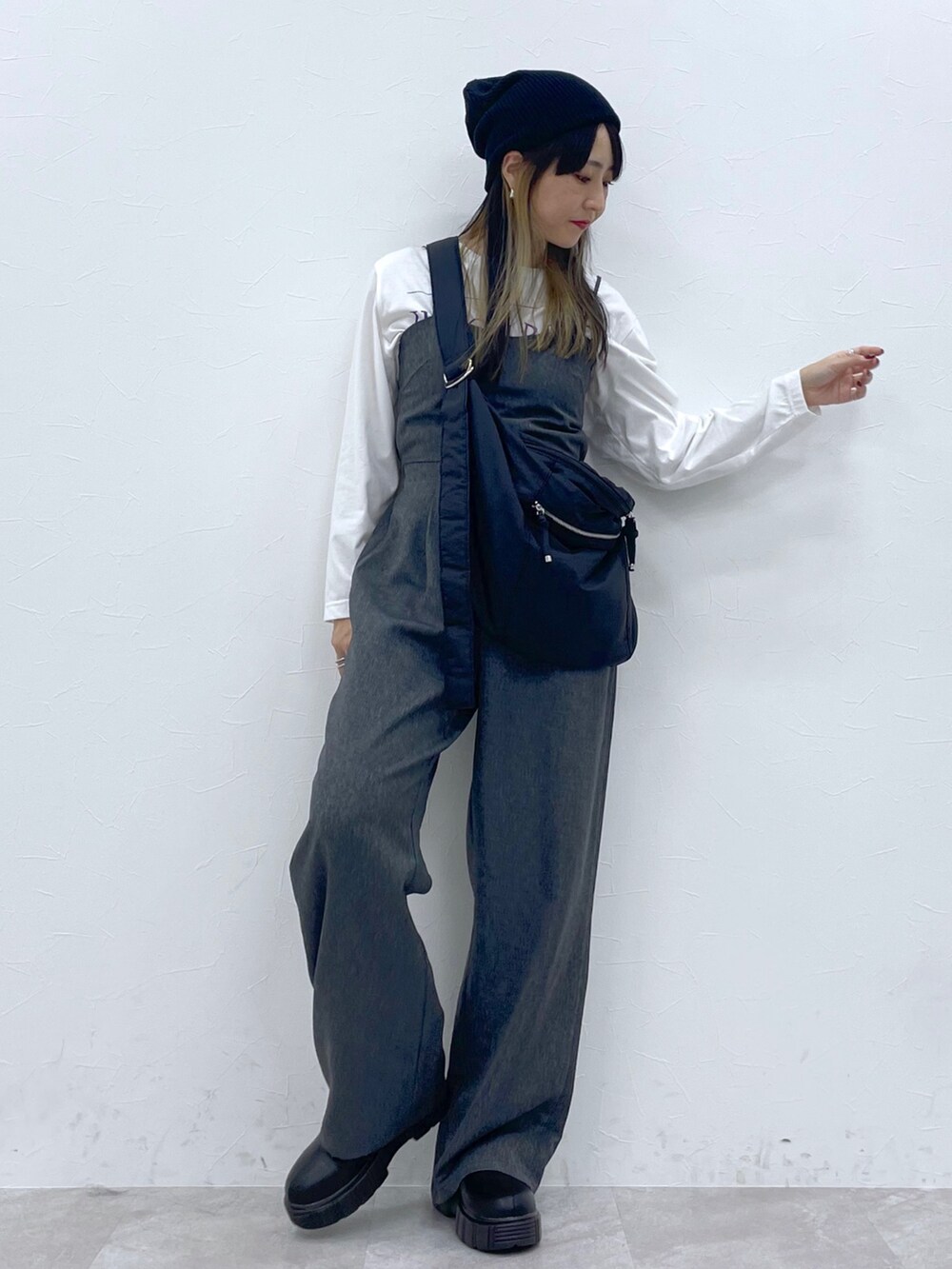 ホワイト系のトップス、ブラック系のサロペット/オーバーオール、ブラック系のブーツを着用したレディースの秋コーディネートの4枚目の写真