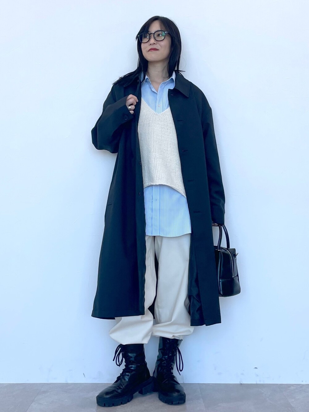 ブラック系のステンカラーコート、ベージュ系のニット/セーター、ブルー系のシャツ/ブラウスを着用したレディースの冬コーディネートの2枚目の写真