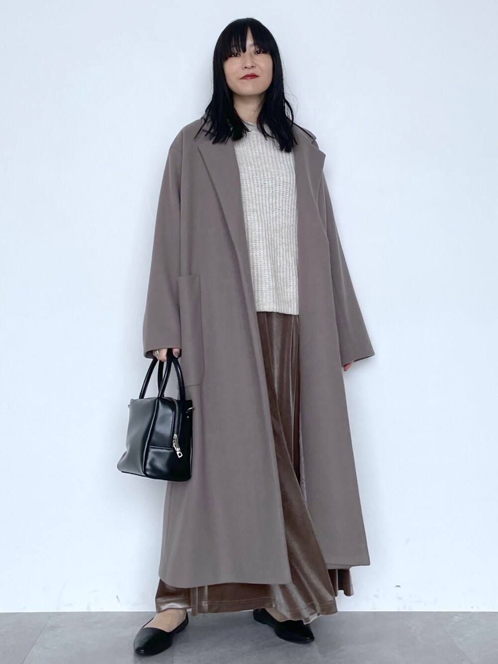 ベージュ系のチェスターコート、ブラック系のショルダーバッグ、ブラウン系のスカートを着用したレディースの冬コーディネートの6枚目の写真