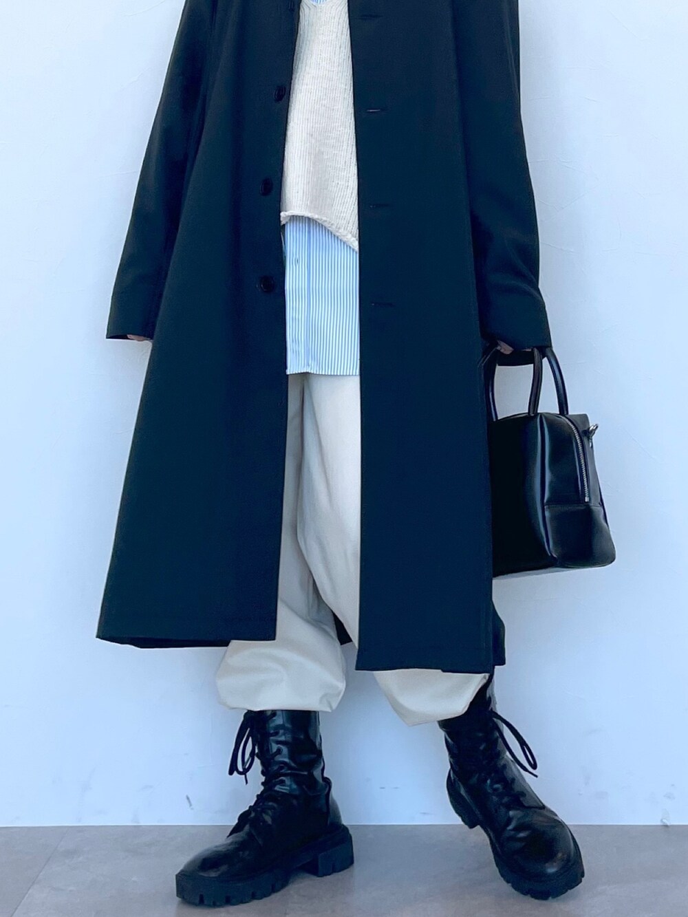 ブラック系のステンカラーコート、ベージュ系のニット/セーター、ブルー系のシャツ/ブラウスを着用したレディースの冬コーディネートの7枚目の写真