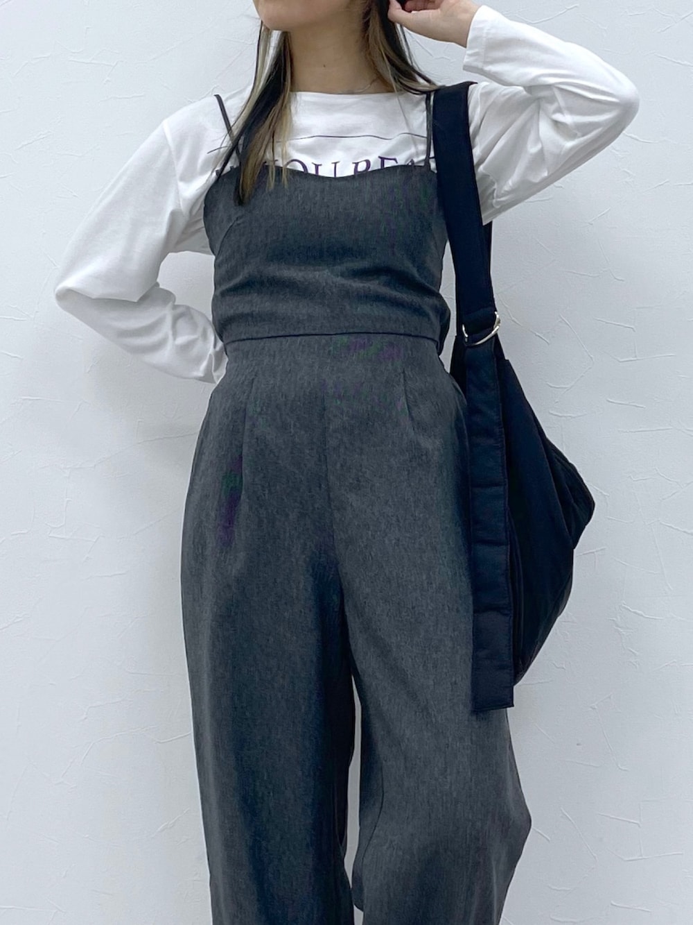 ホワイト系のトップス、ブラック系のサロペット/オーバーオール、ブラック系のブーツを着用したレディースの秋コーディネートの5枚目の写真