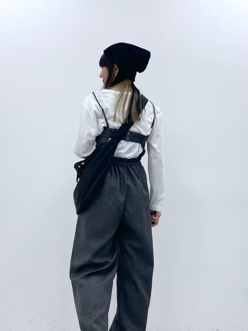 ホワイト系のトップス、ブラック系のサロペット/オーバーオール、ブラック系のブーツを着用したレディースの秋コーディネートの3枚目の写真